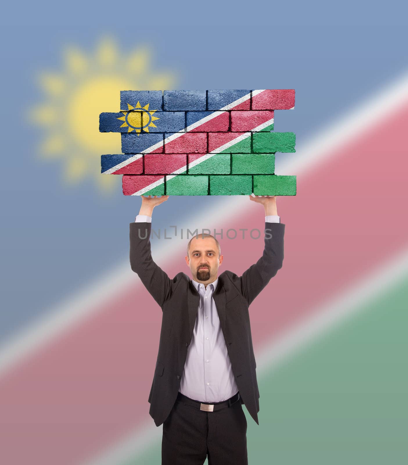 Businessman holding a large piece of a brick wall, flag of Namibia, isolated on national flag