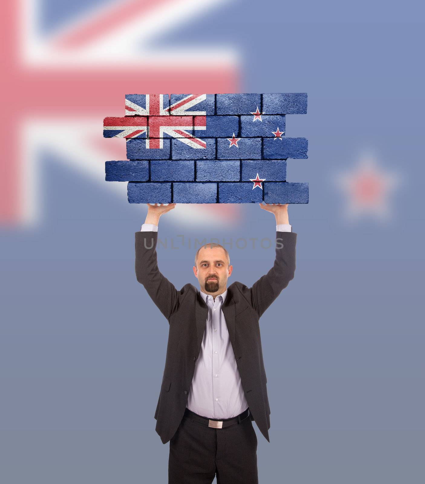 Businessman holding a large piece of a brick wall, flag of New Zealand, isolated on national flag