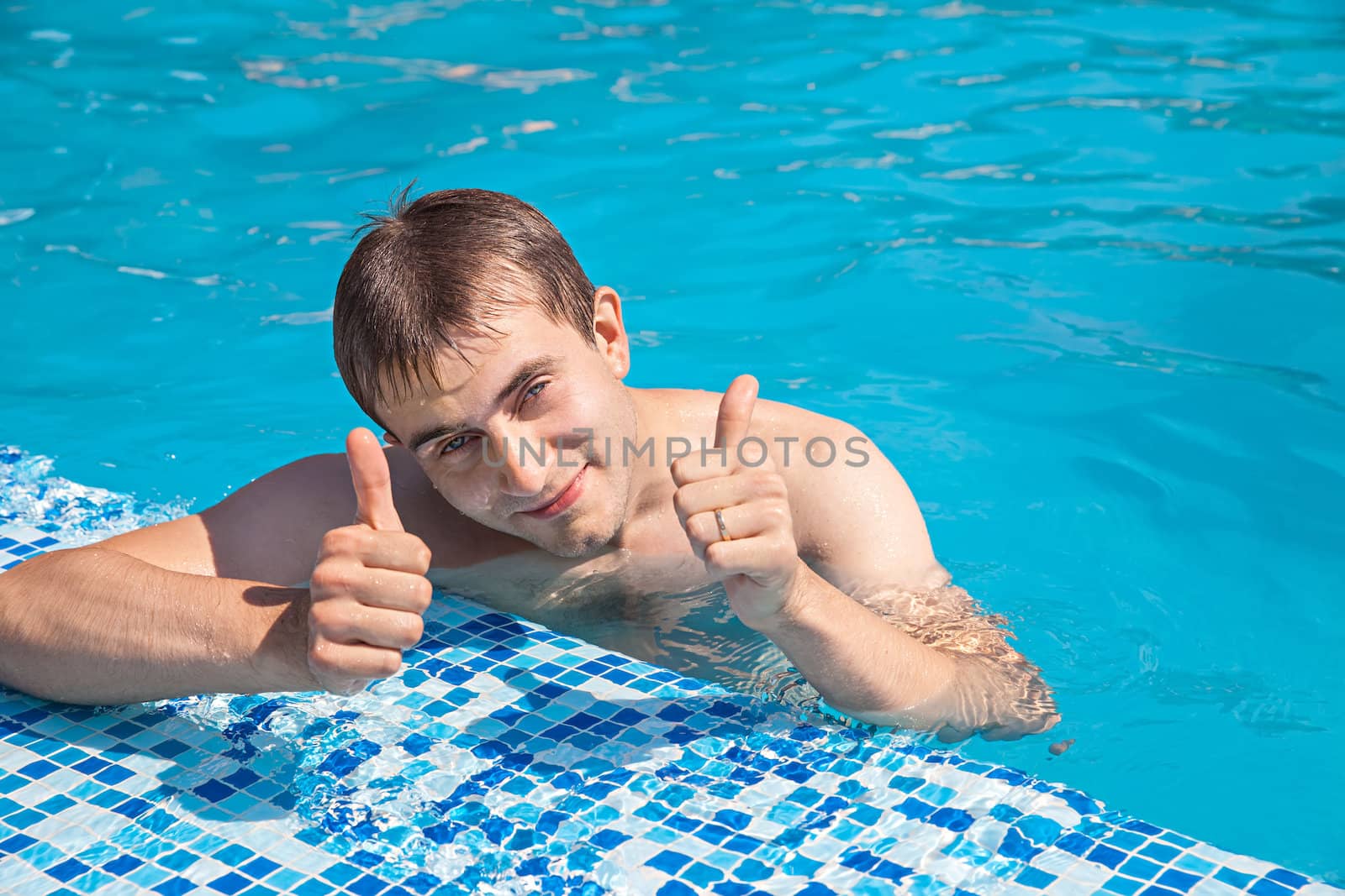Healthy lifestyle. The young man is swimming in a pool on a sunny day