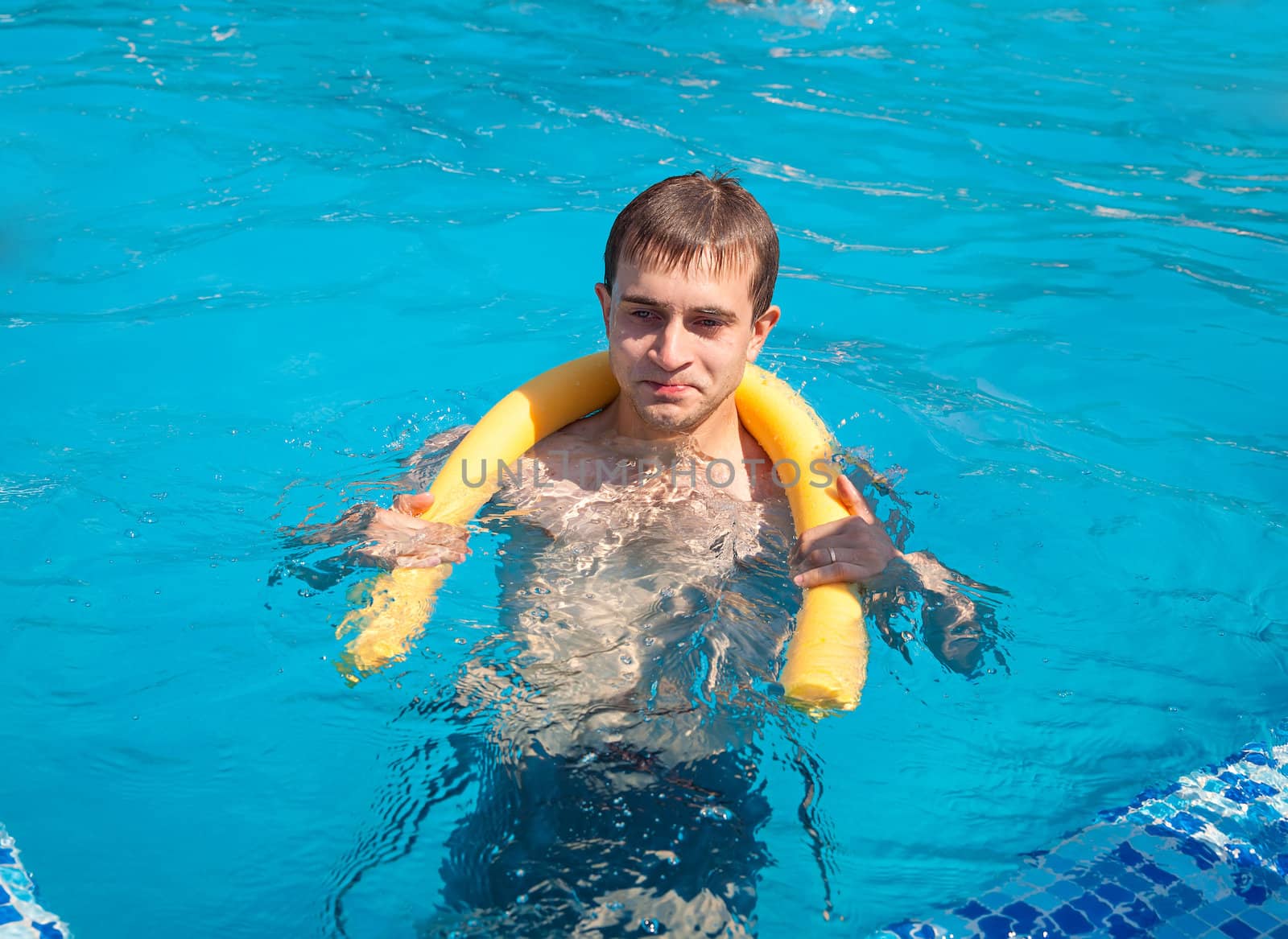 Healthy lifestyle. The young man is swimming in a pool on a sunny day