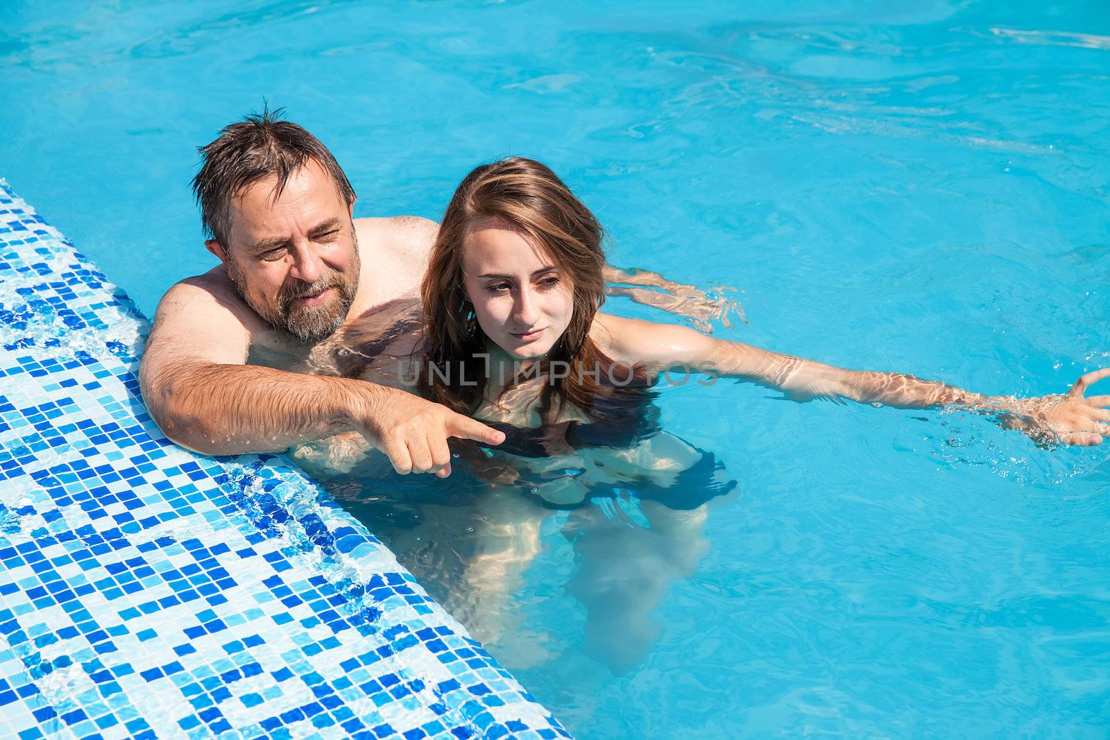 Happy family. Father and daughter swimming in the pool on a sunny day.