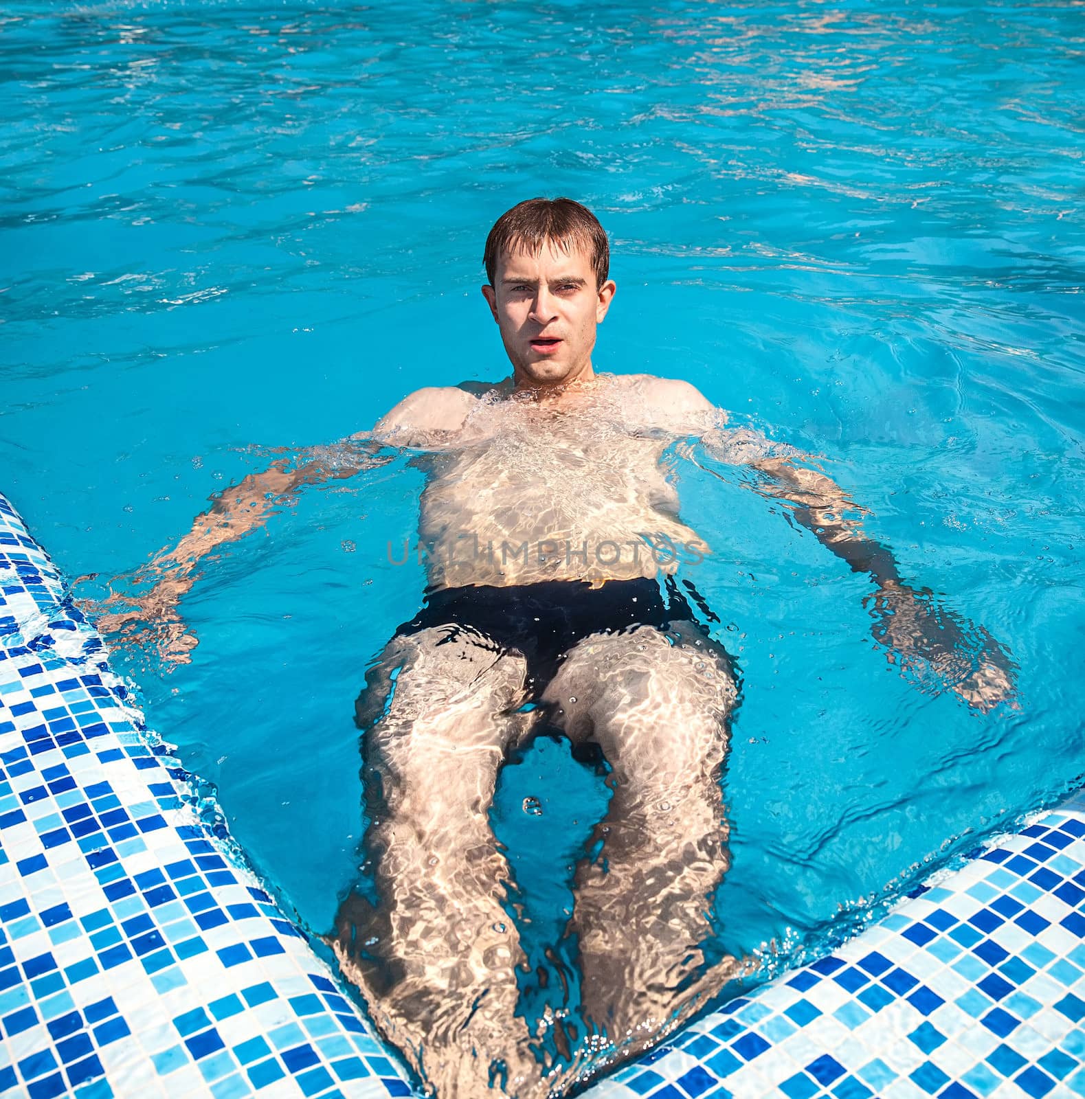 Healthy lifestyle. The young man is swimming in a pool on a sunny day