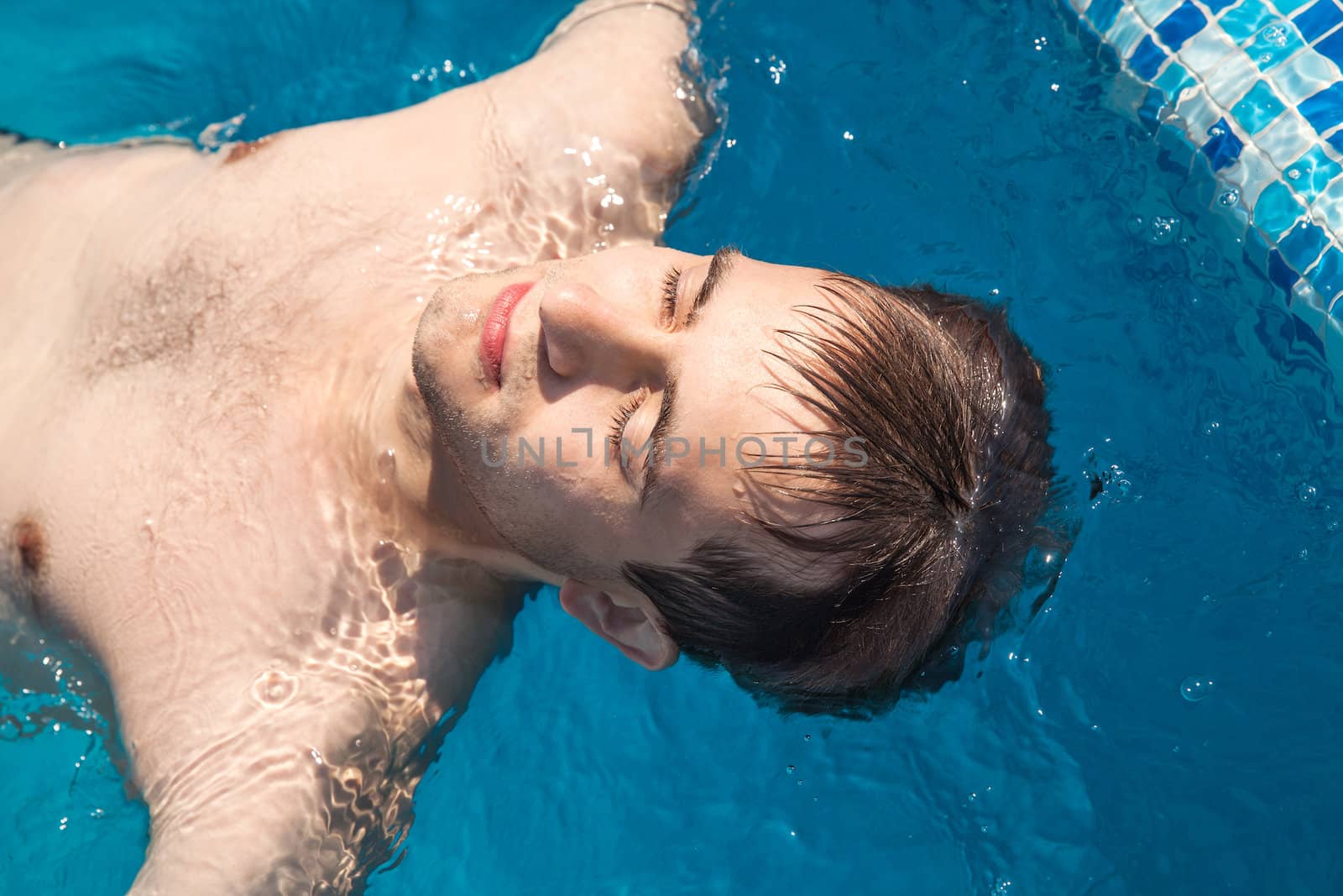 Healthy lifestyle. The young man is swimming in a pool on a sunny day