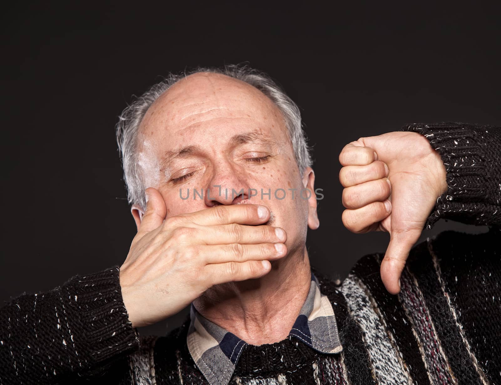 An elderly man with closed eyes closes her mouth and shows thumb down