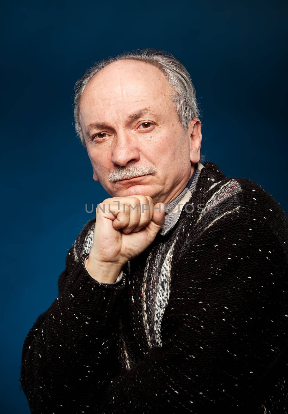 Portrait of handsome senior man prop up the head with his fist