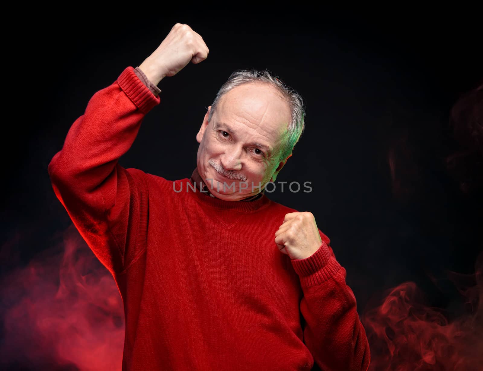 Successful old happy man in a red sweater gestures