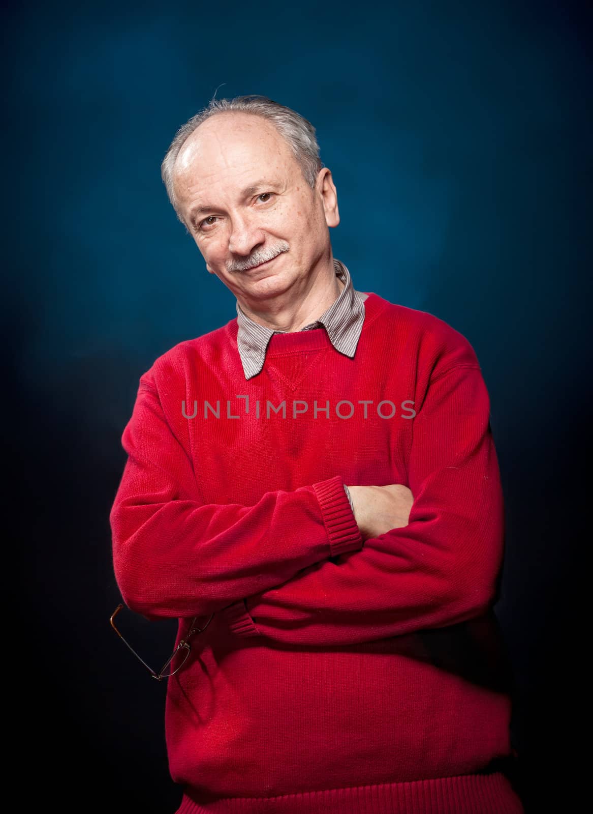 Portrait of a successful elderly man in a red sweater on a dark blue background