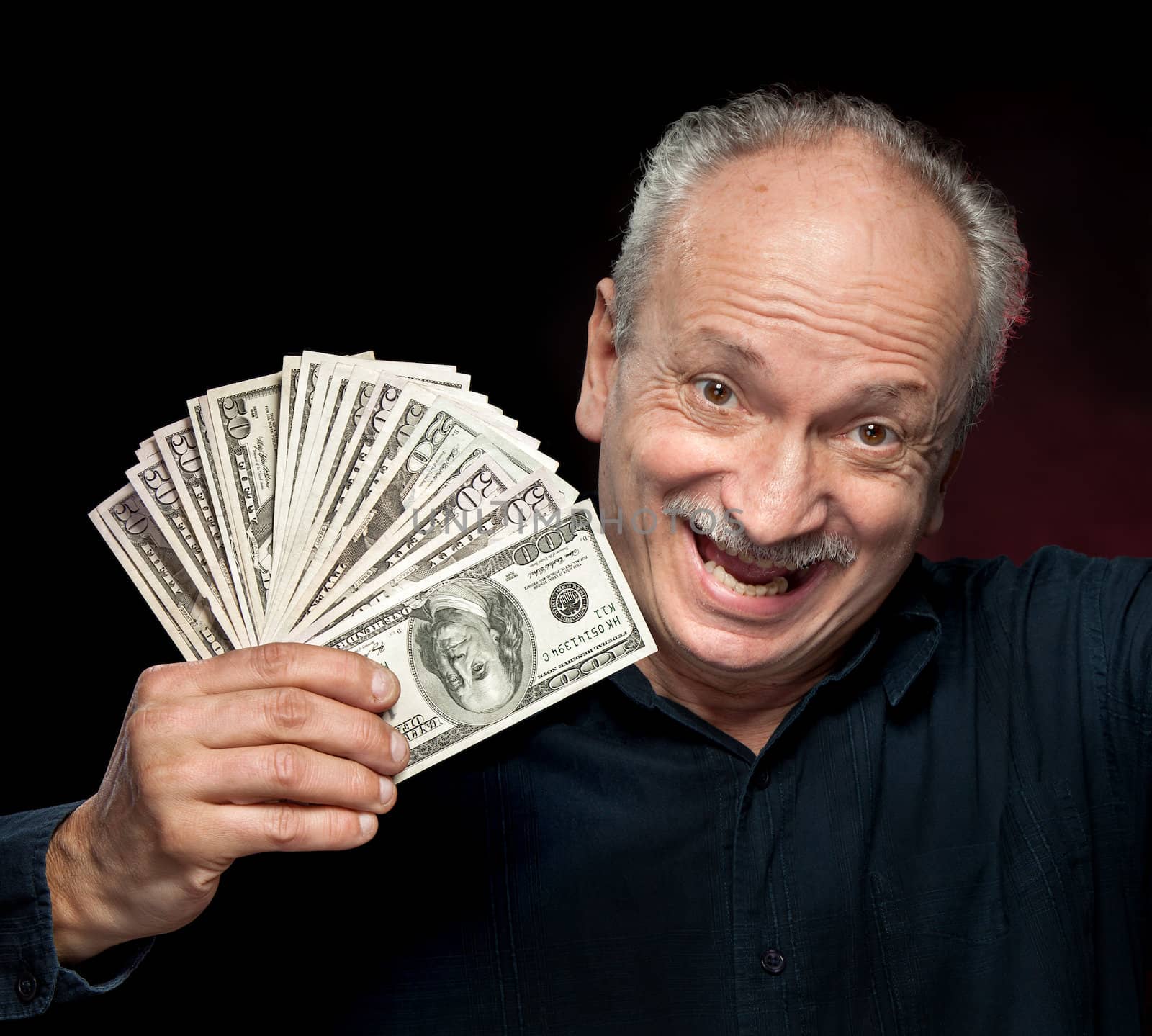 An elderly happyl businessman showing fan of money  