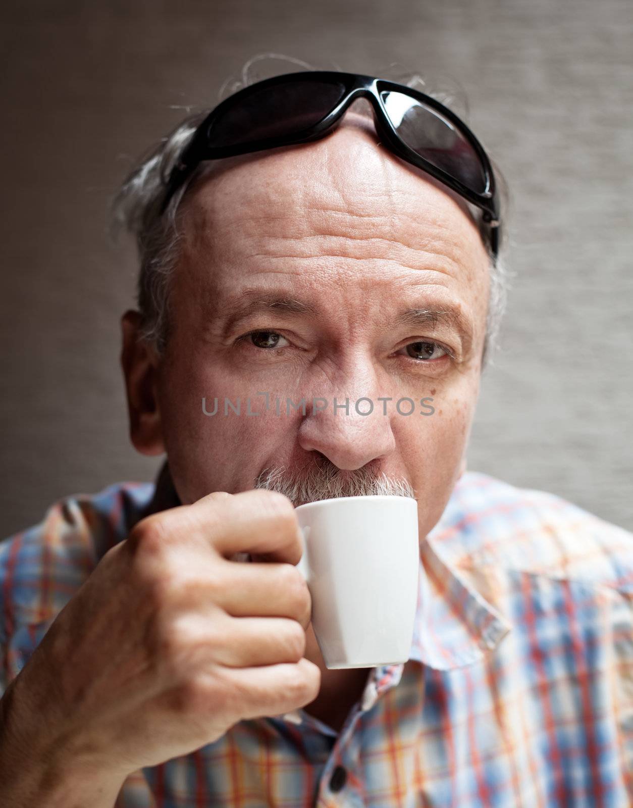 Portrait of smart old man drinking cup of coffee