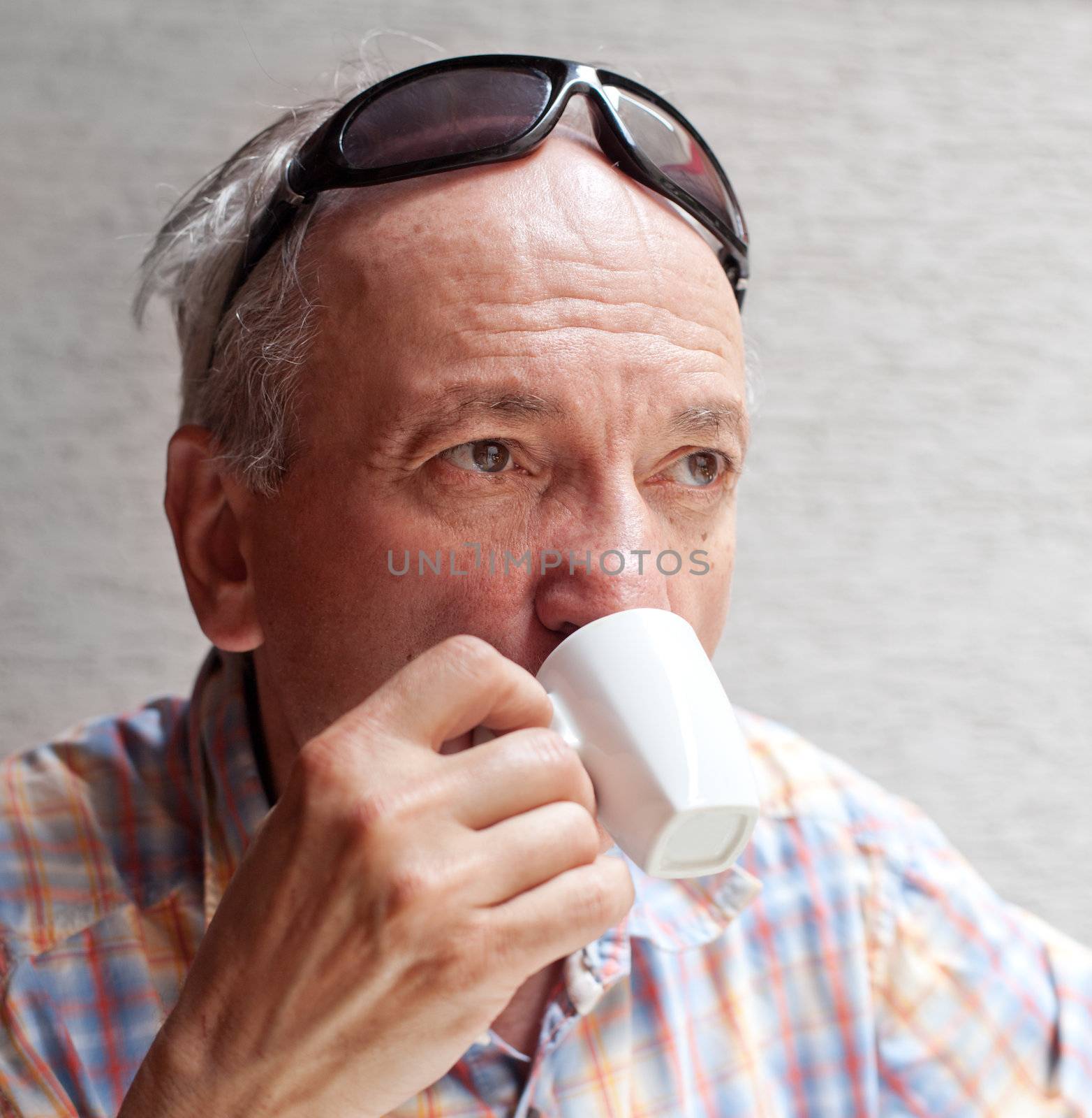 Portrait of smart old man drinking cup of coffee