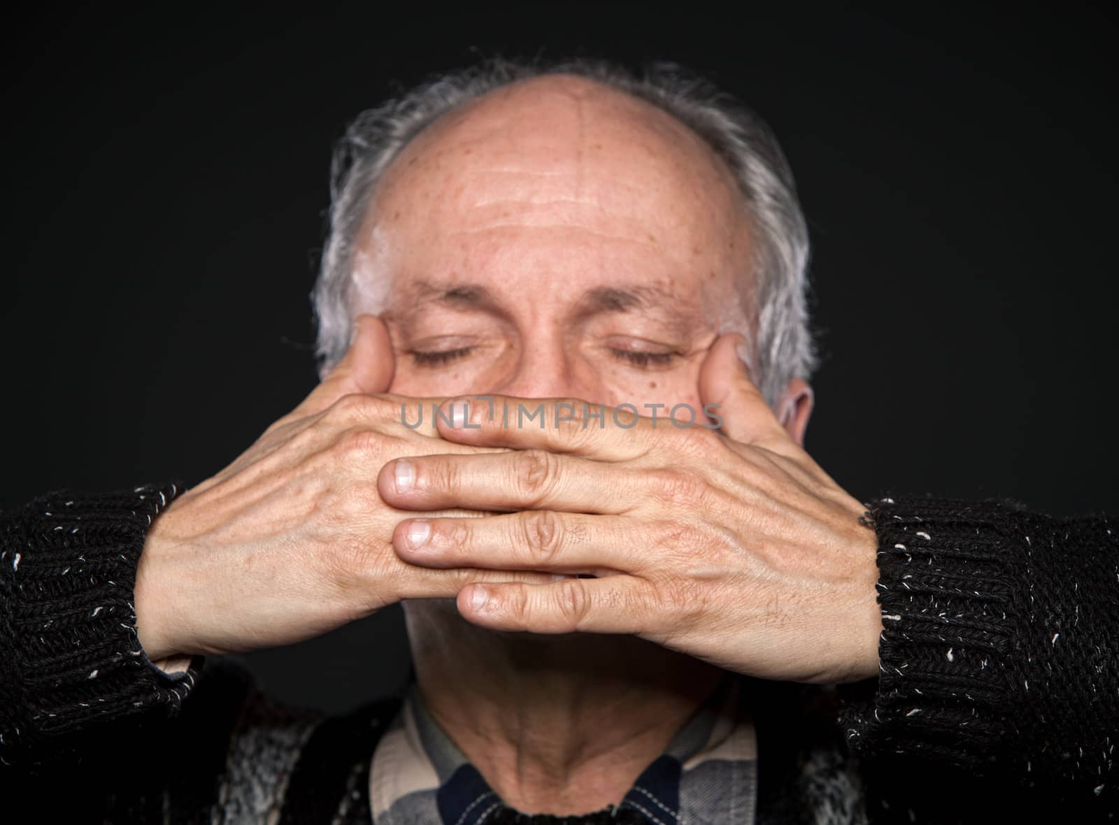 An elderly man with closed eyes closed mouth with hands. Focus on hands