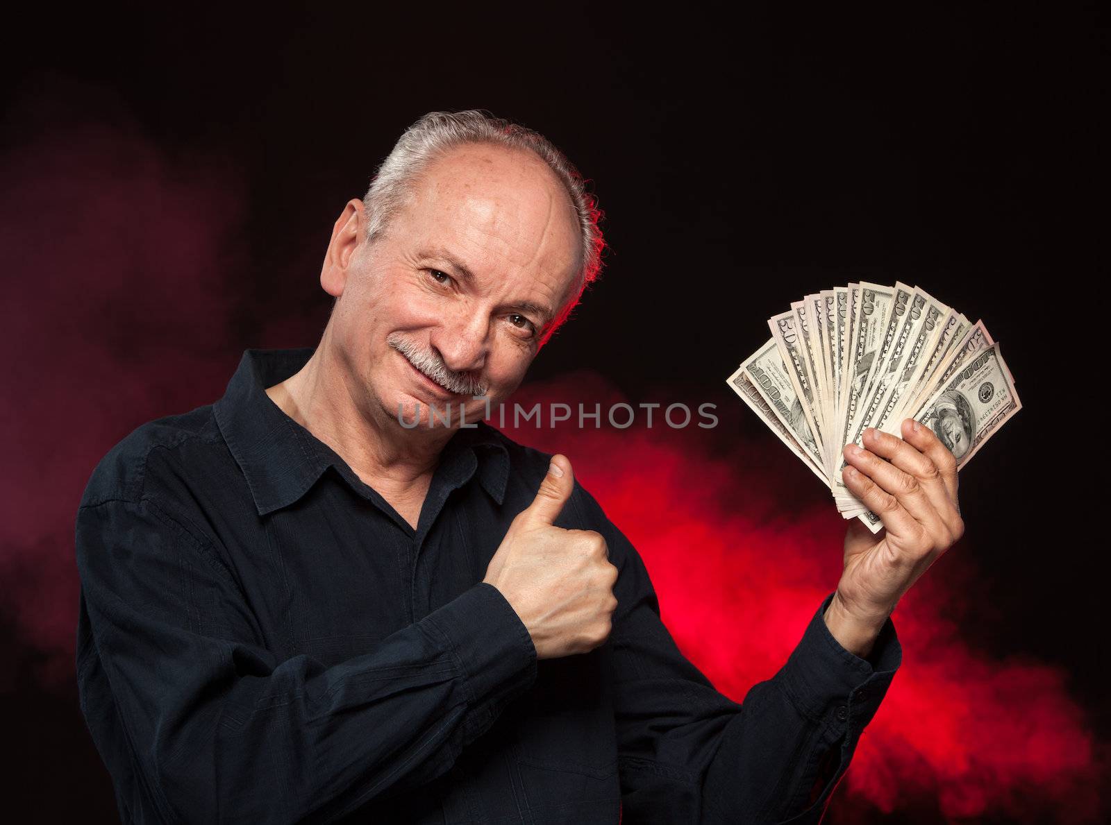 Lucky old man holding with pleasure group of dollar bills