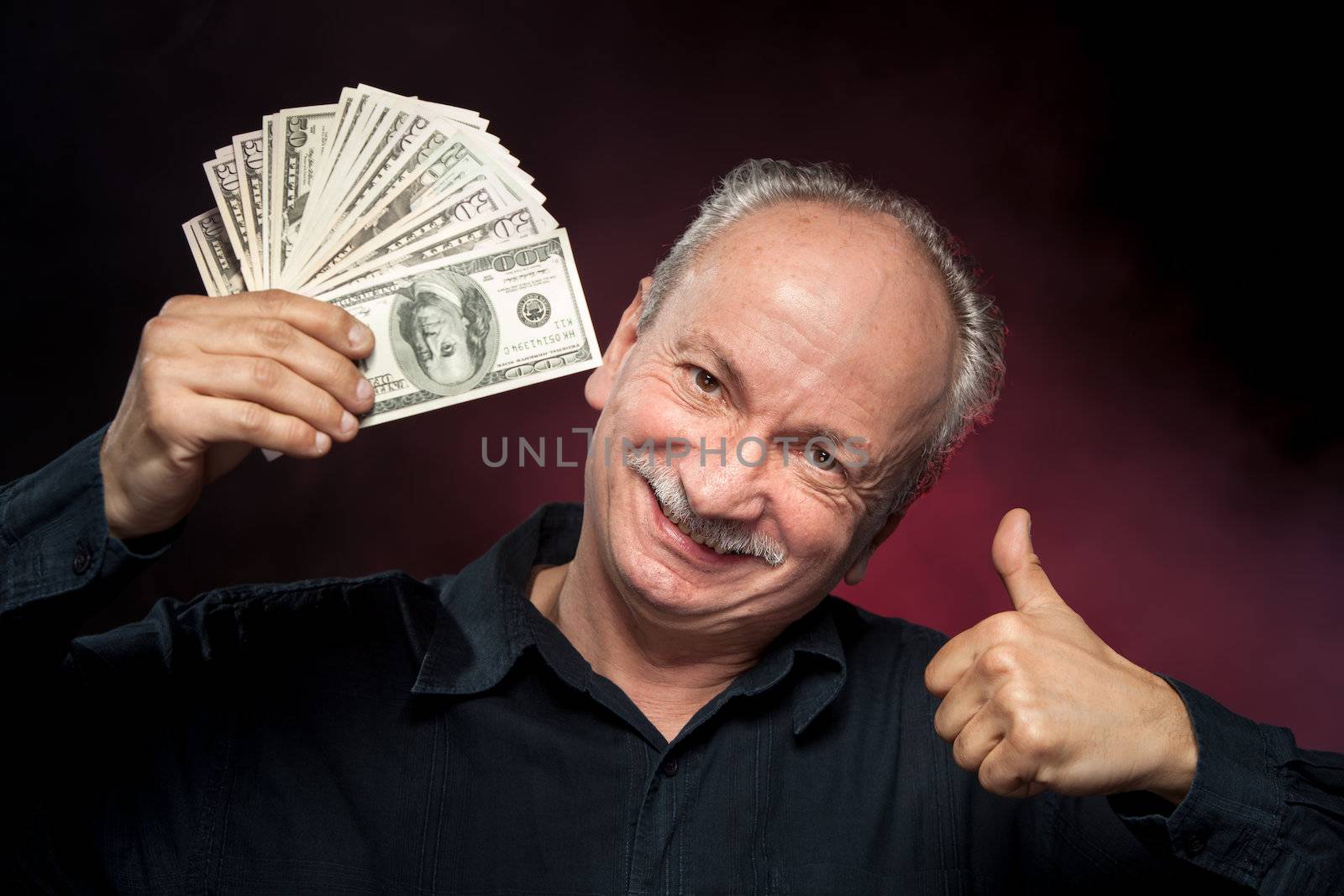 Happy elderly man showing fan of money and sign OK with fingers