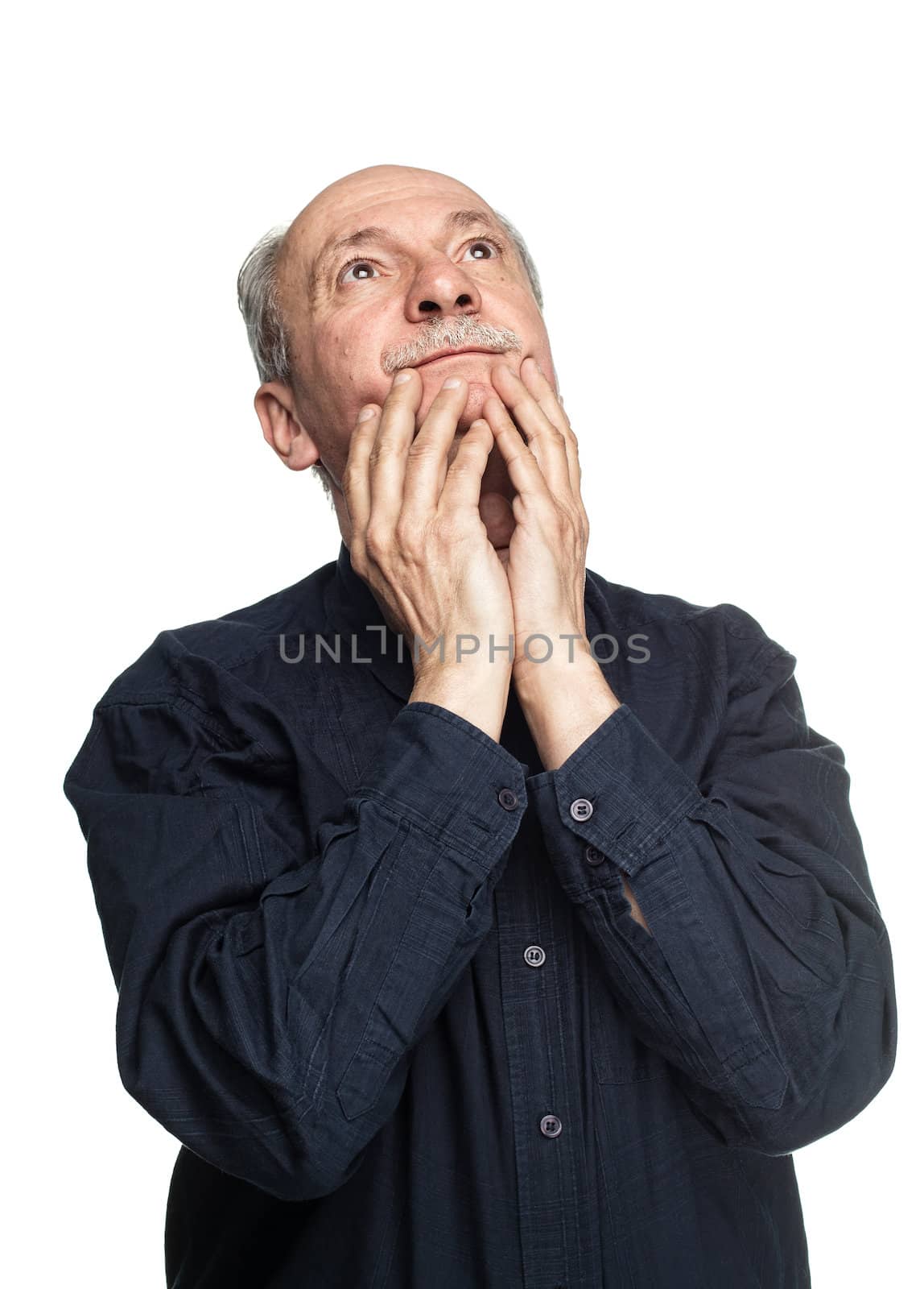 Elderly man with hands near his face  looking up thinking