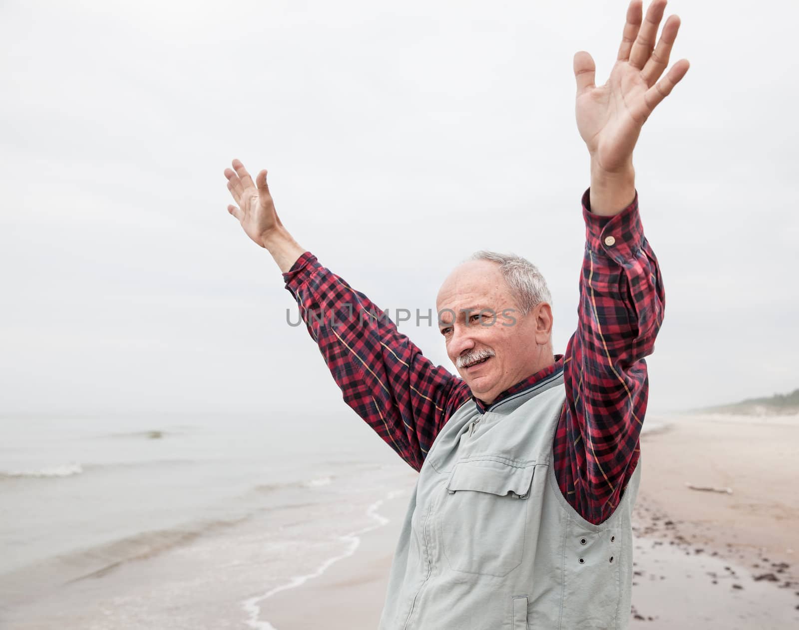 peaceful carefree older man with outstretched arms the coast at foggy day