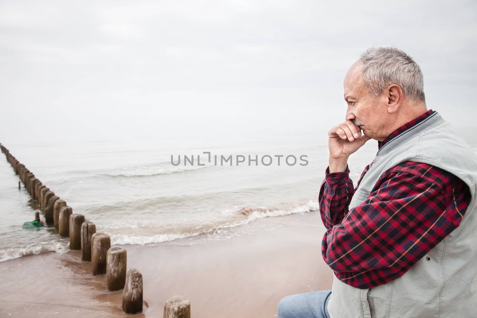 Thoughtful elderly man standing on the beach by palinchak