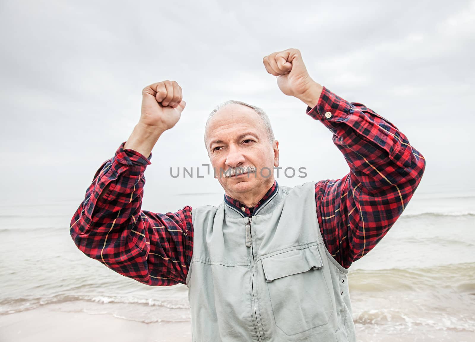 older man with hands up at the coast  by palinchak
