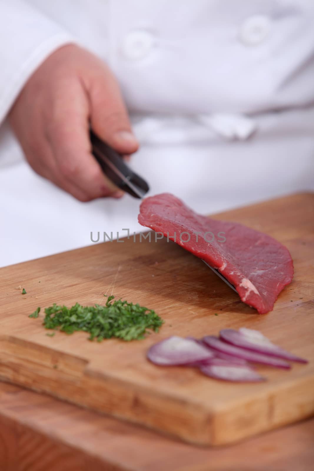 Butcher with raw piece of piece by phovoir