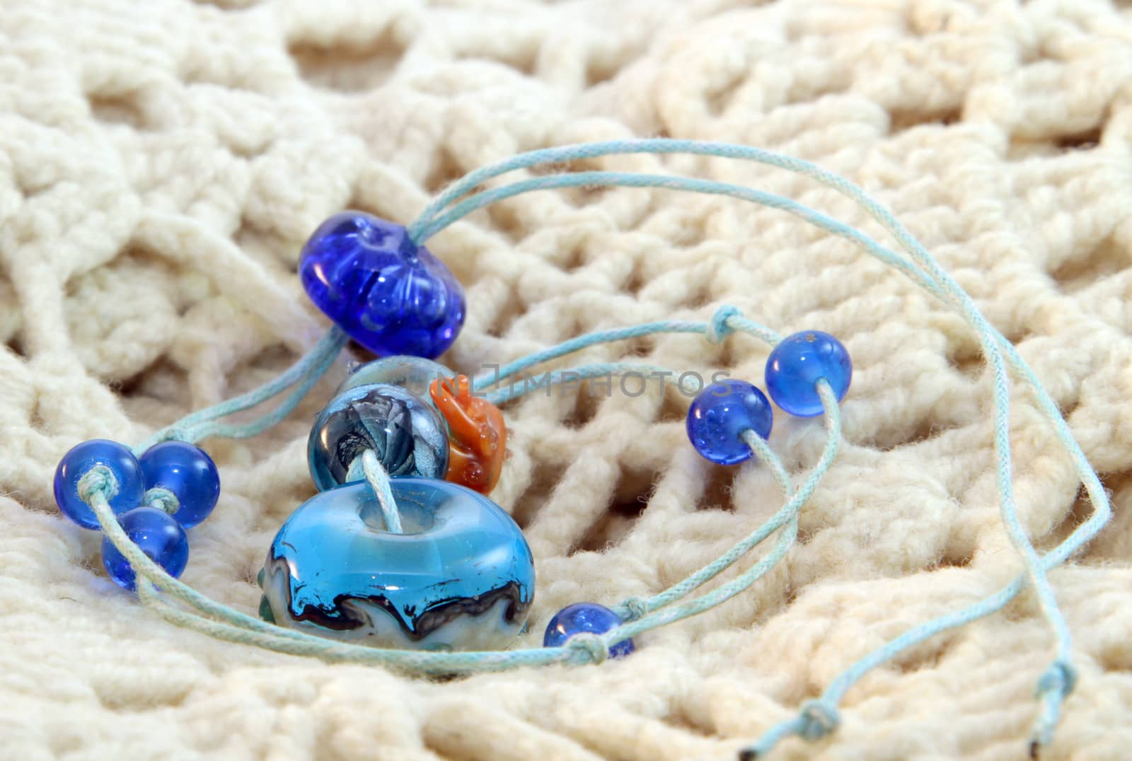 Blue beaded pendant handmade on the white knitted background