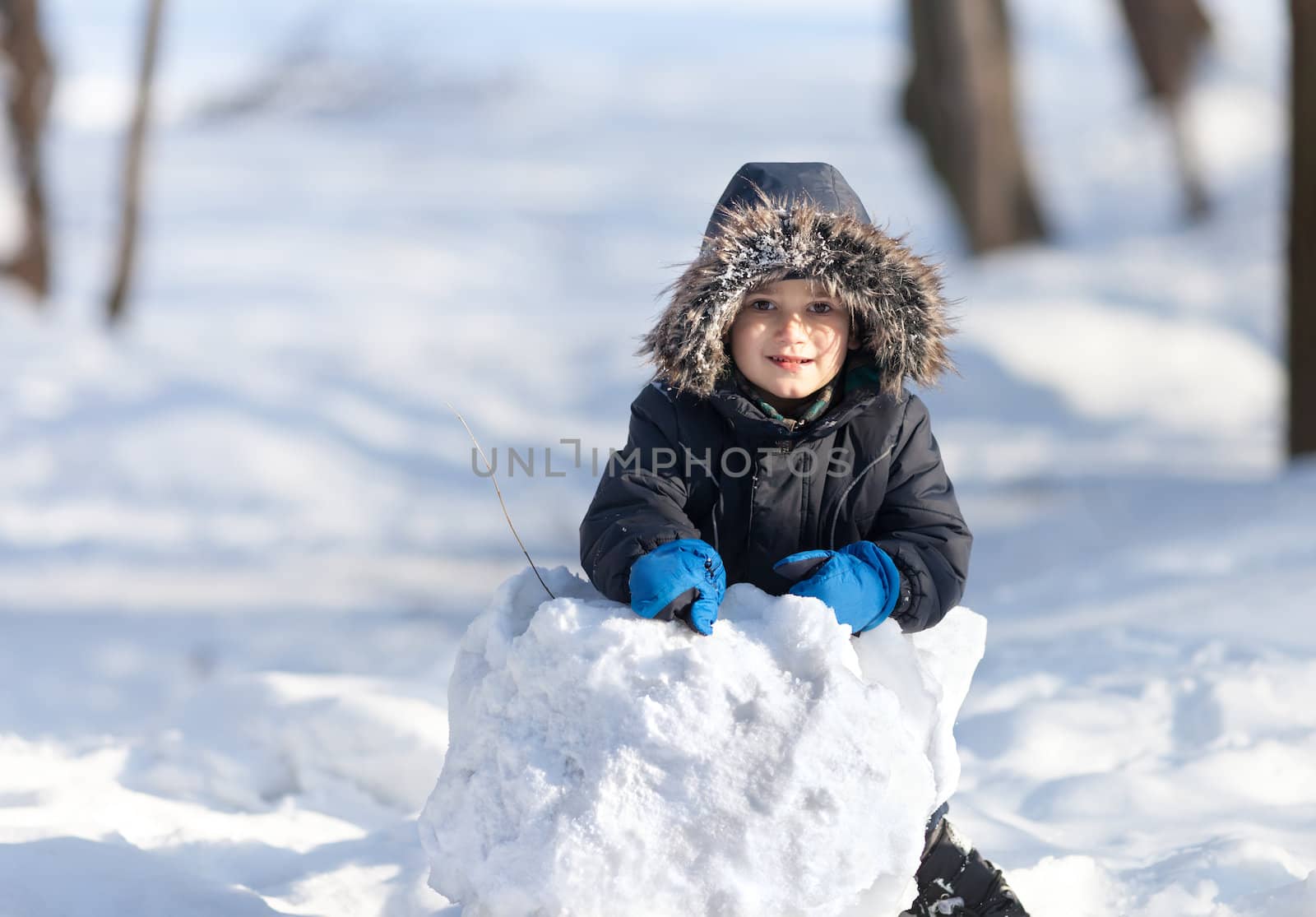 Cute boy playing with snow in the winter park by palinchak