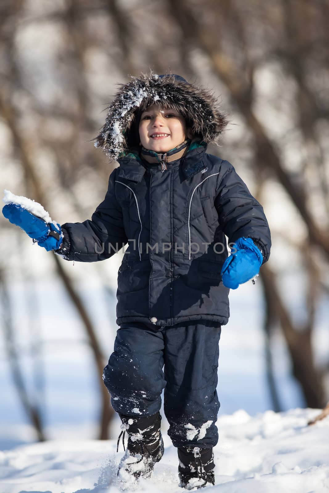Cute boy walk in the winter park in sunny day