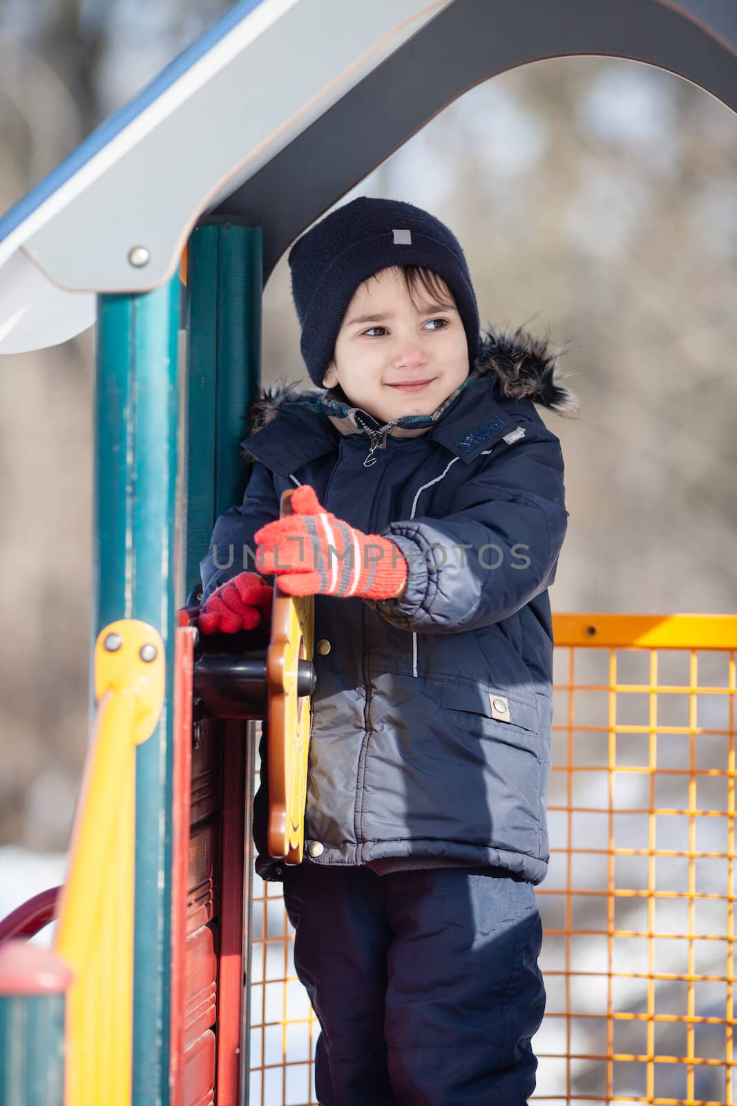 Portrait of cute boy playing in the winter park in sunny day