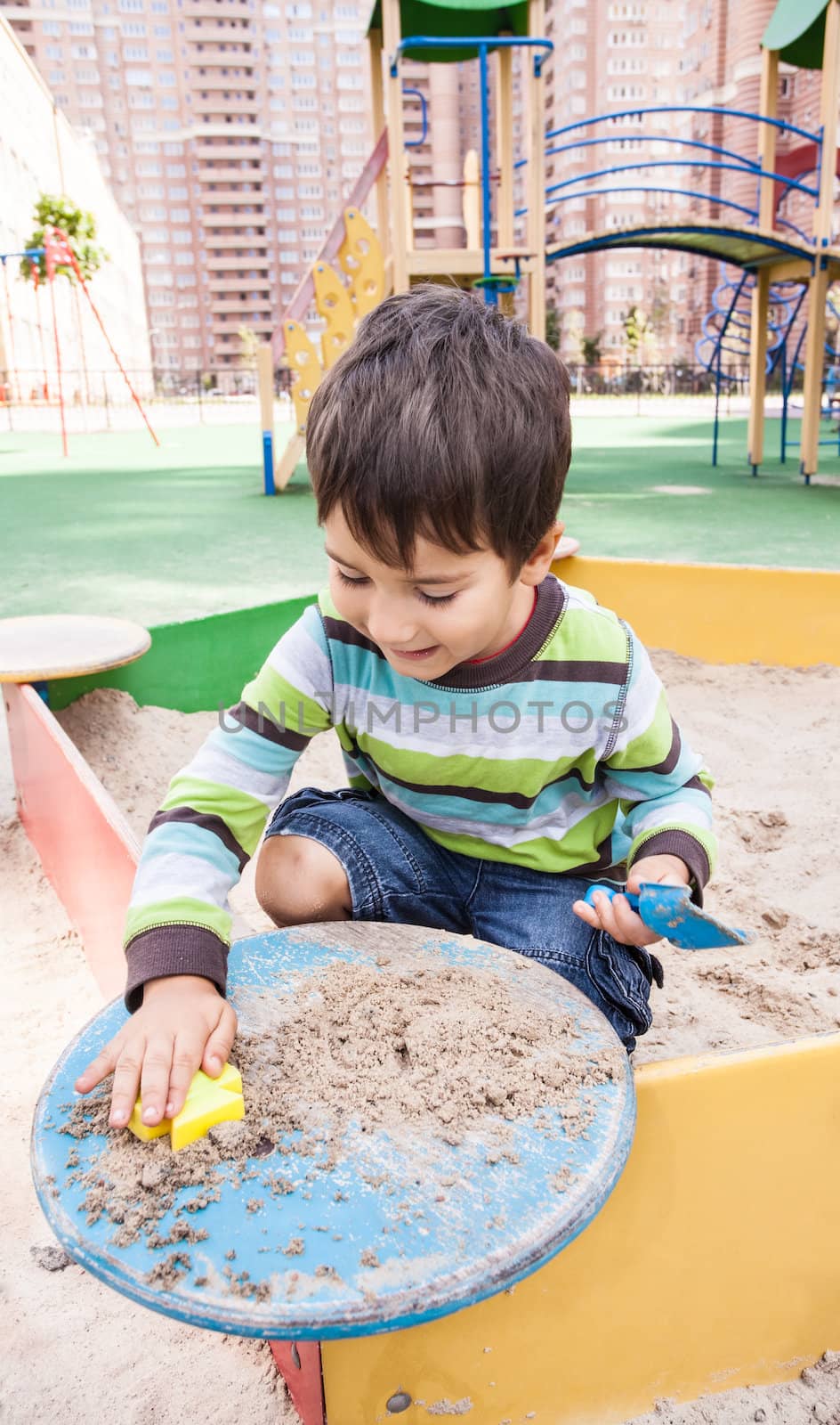 Cute boy playing in sandbox with a sand toys
