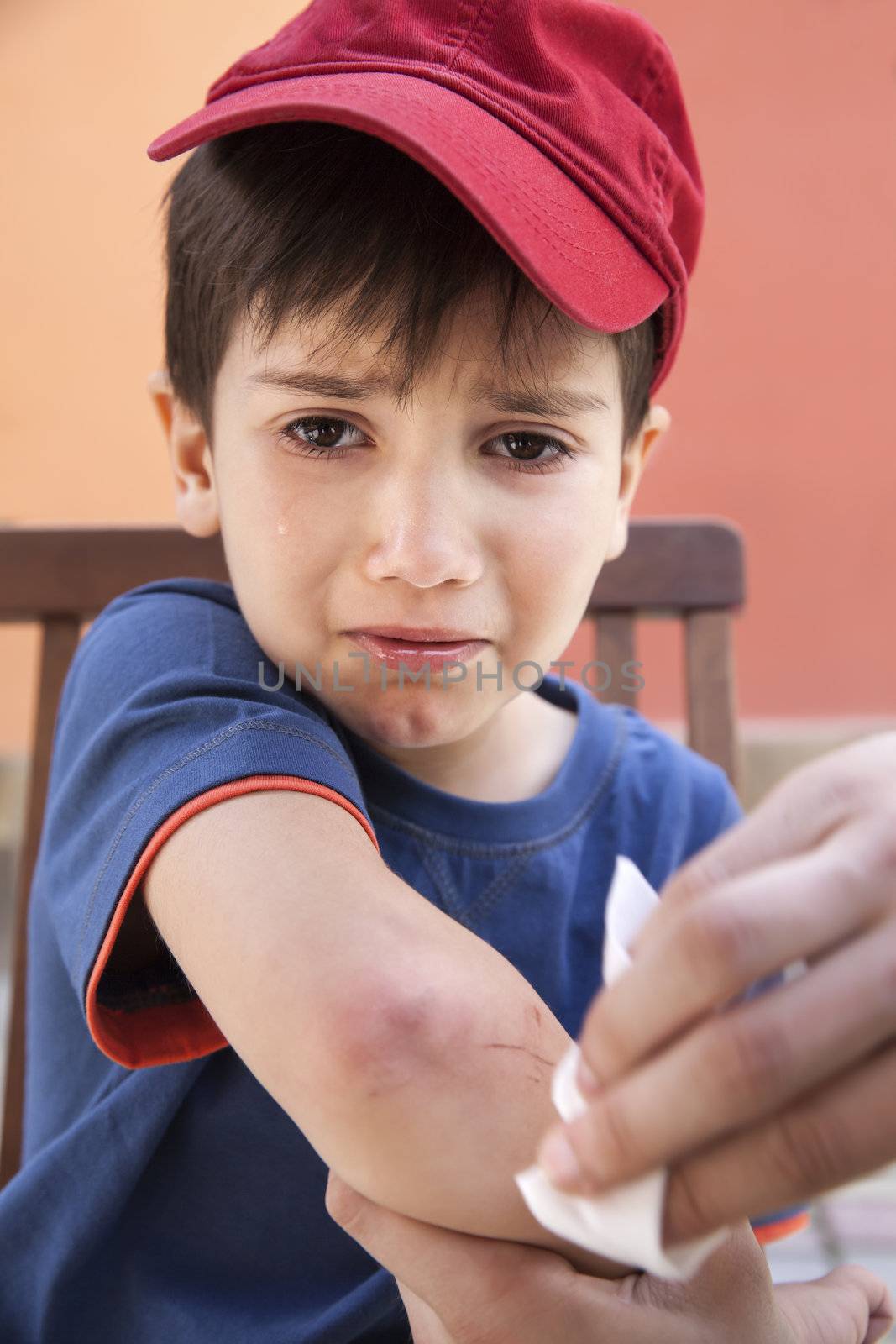 Small boy crying in pain injuring his hand. Father provides first aid