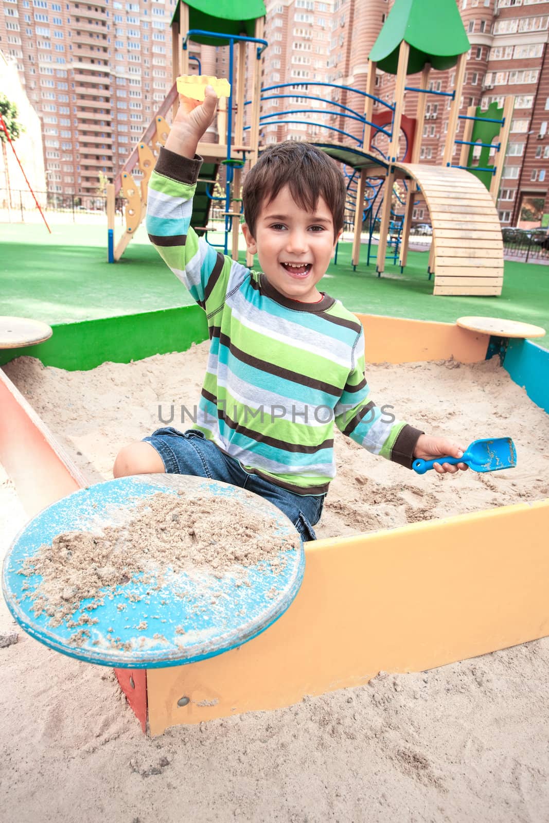 Cute boy playing in sandbox with a sand toys