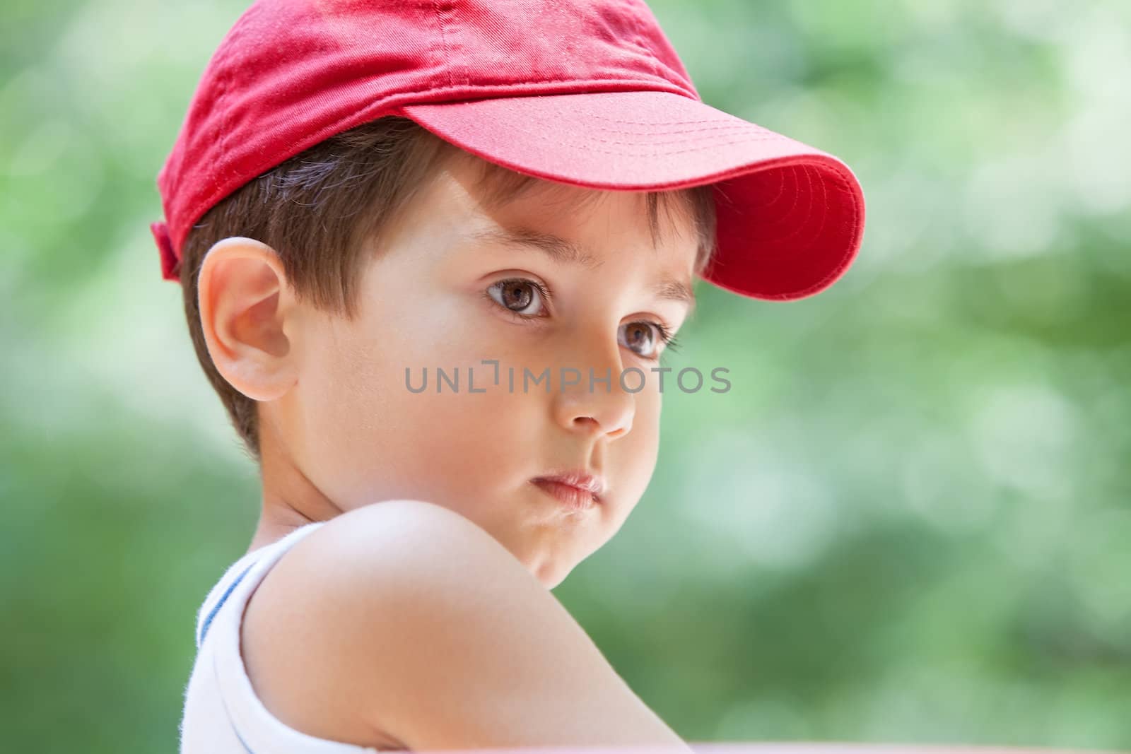 Portrait of a 3-4 years boy in a red cap on the blurred natural background