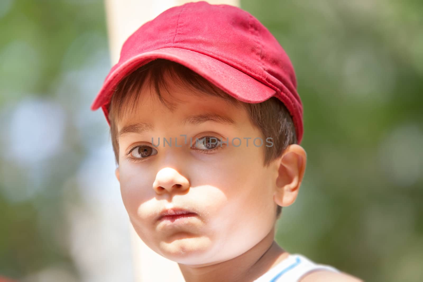 Portrait of a 3-4 years boy in a red cap on the blurred natural background