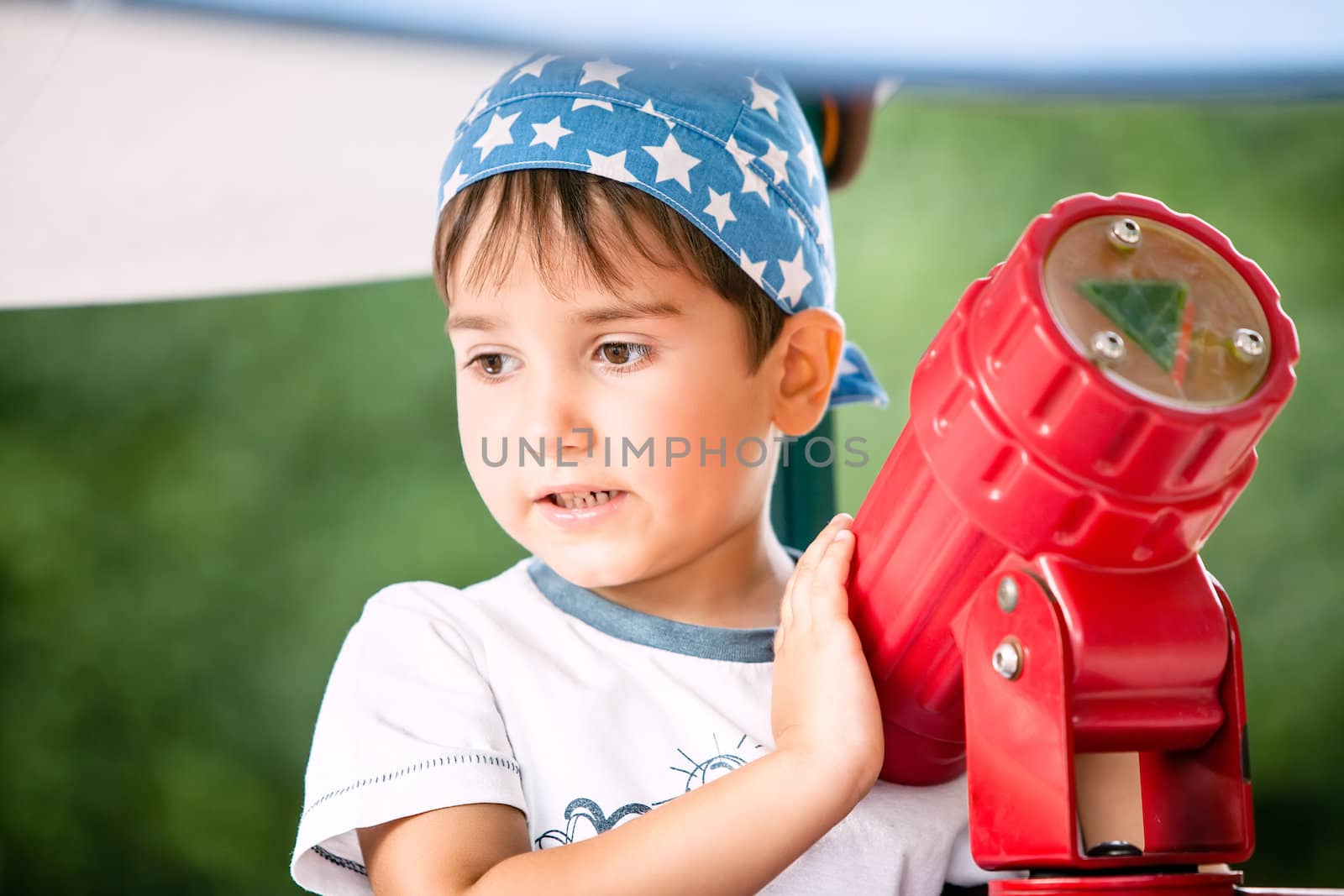 Little boy playing with a toy telescope at the playground