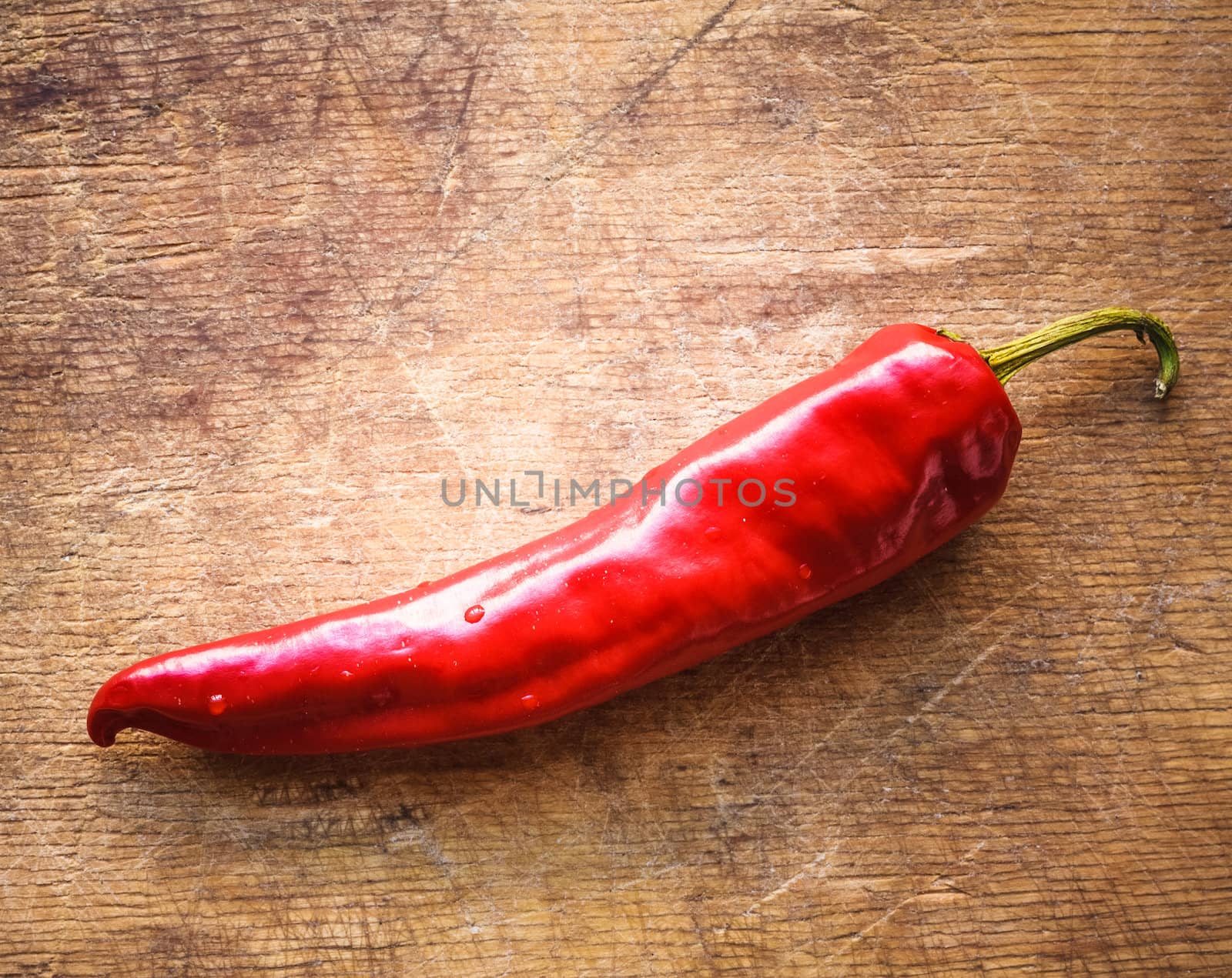 Red hot chili peppers on old wooden table surface texture background