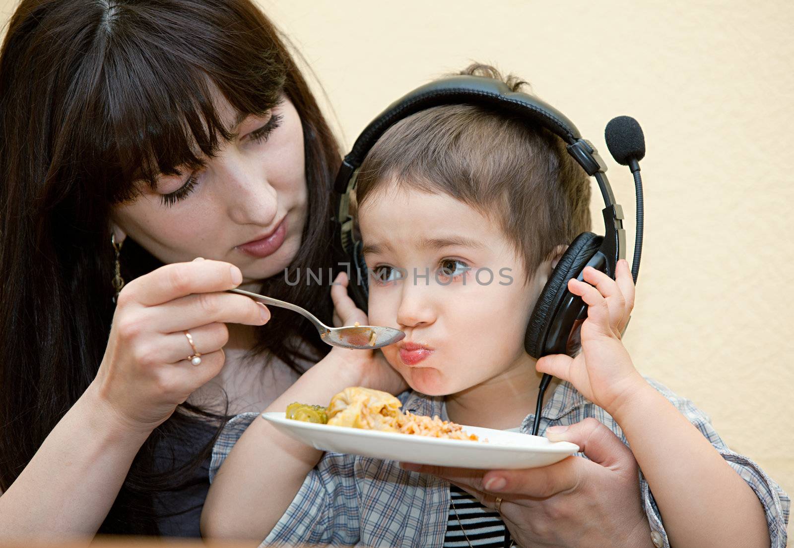 Mother feeding her baby. Baby in headphones