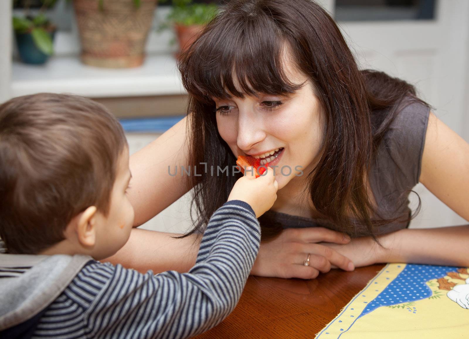 Little boy gives a piece of red pepper to mother
