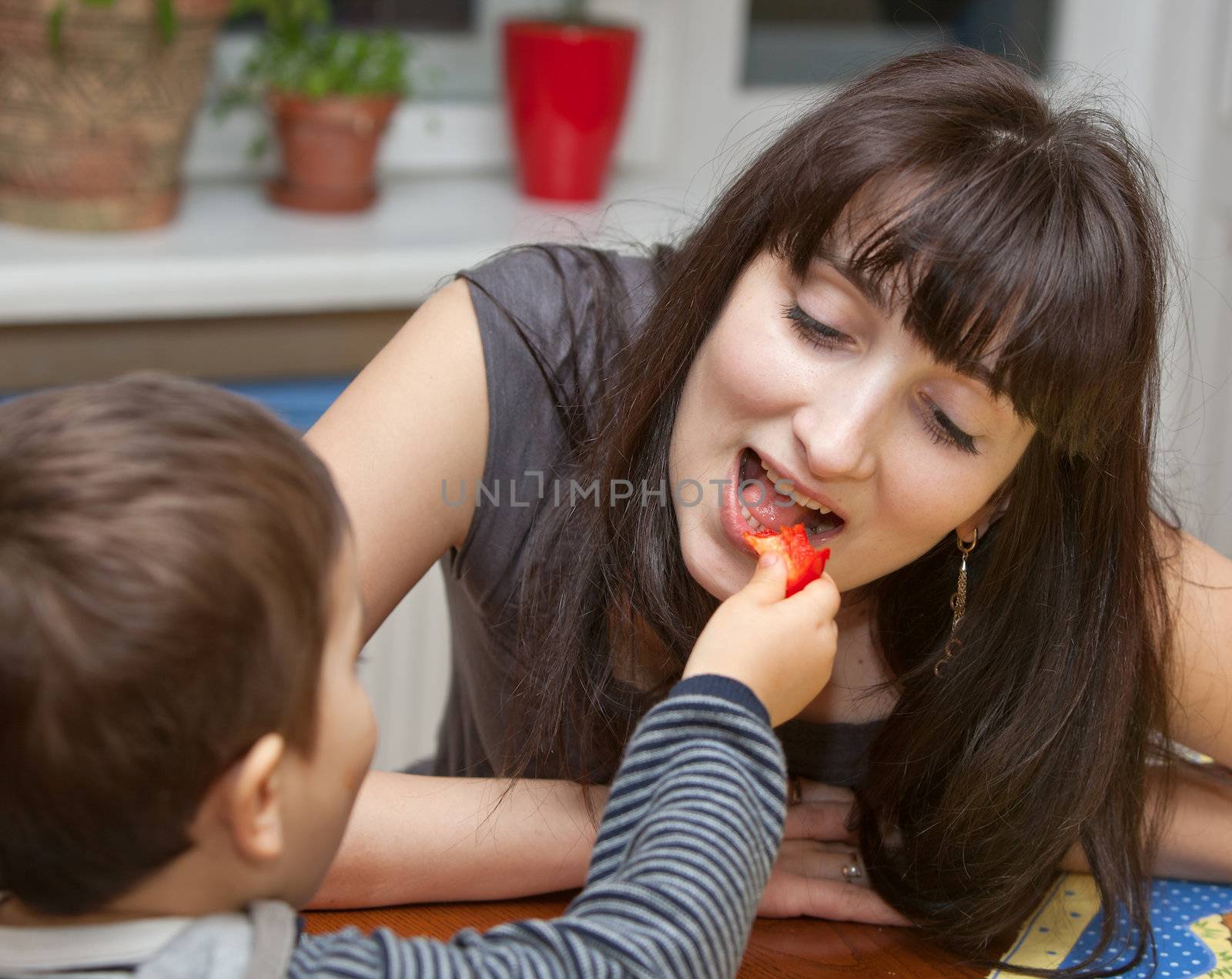 Little boy gives a piece of red pepper to mother