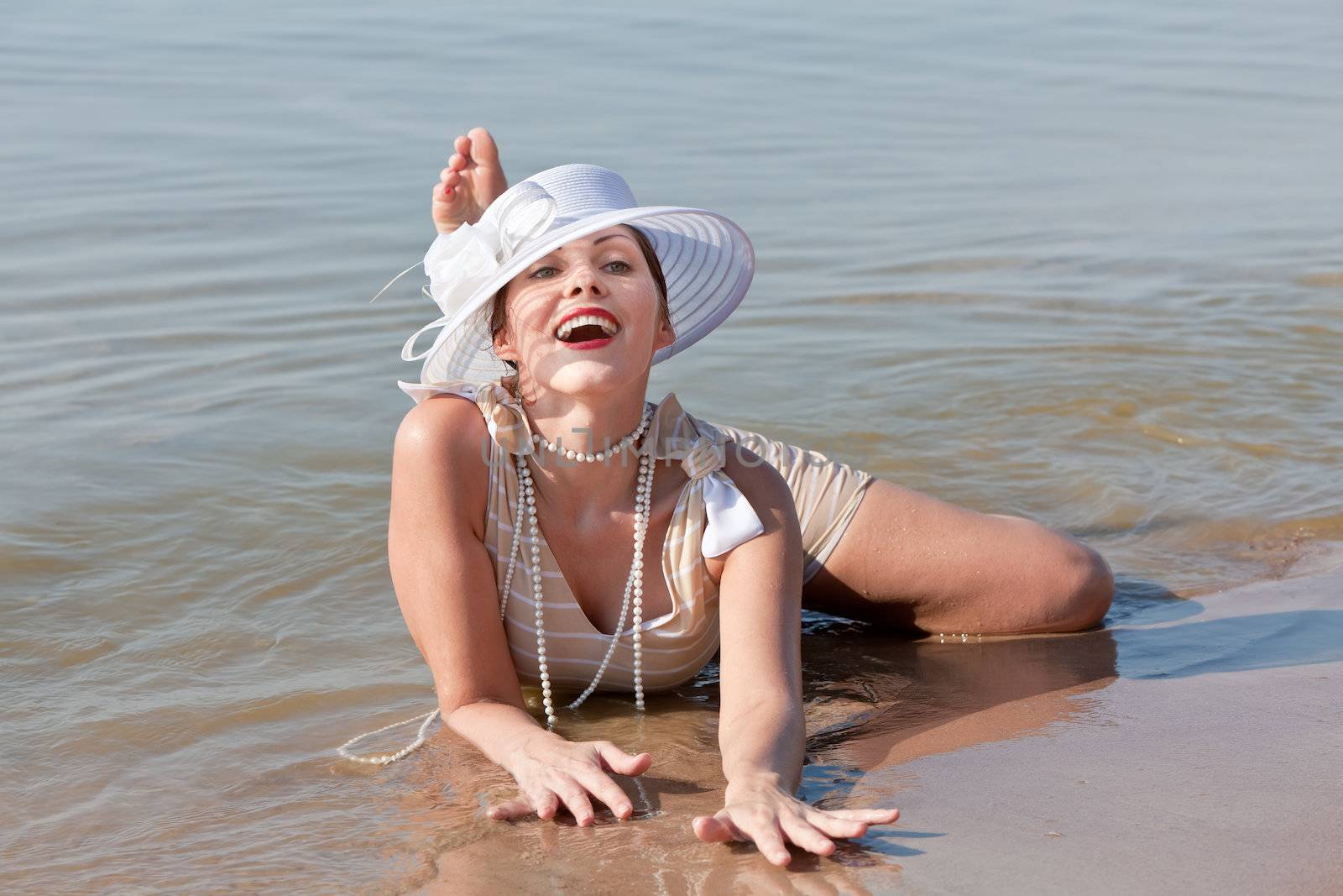 Woman in a striped retro bathing suit in the white hat posing against the sea