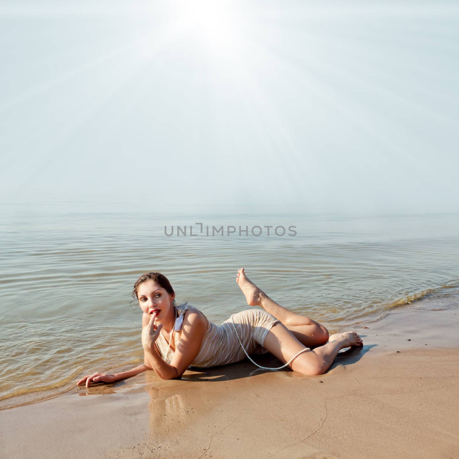 Woman in a striped retro bathing suit in the white hat posing against the sea
