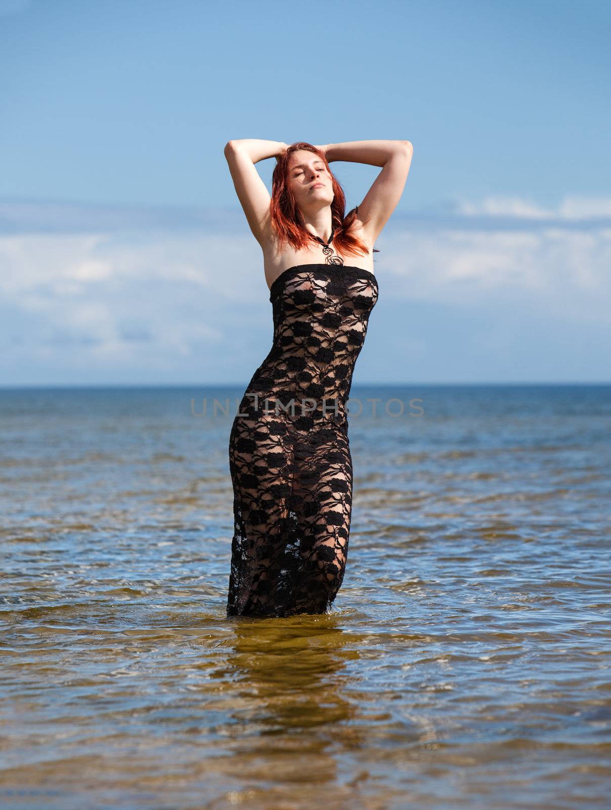 Young woman in black lace dress against the sea
