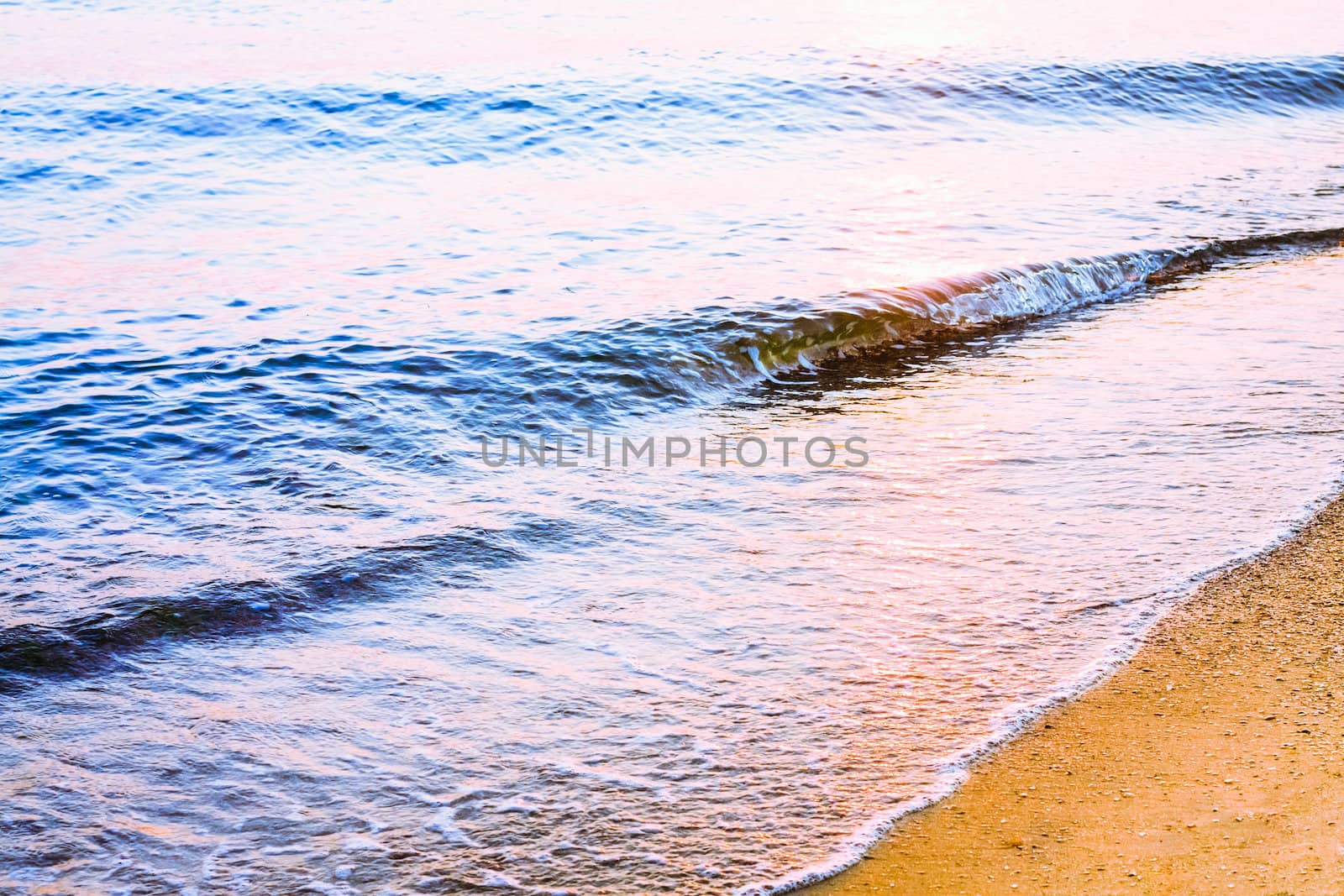 Soft sea ocean waves wash over golden sand background. Sunset, sunrise