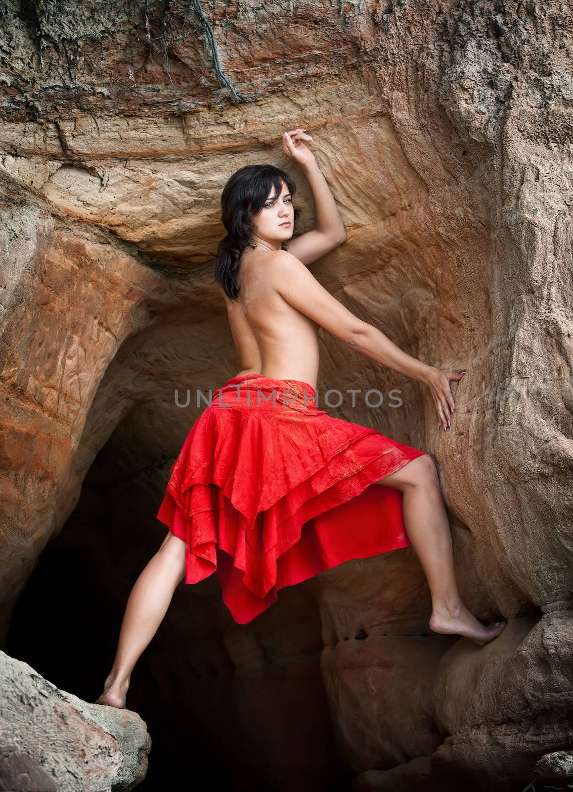 Girl in red dress standing on sandstone and poses