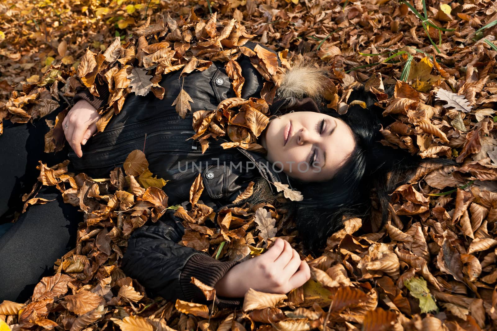 Young woman lying in fallen autumn leaves