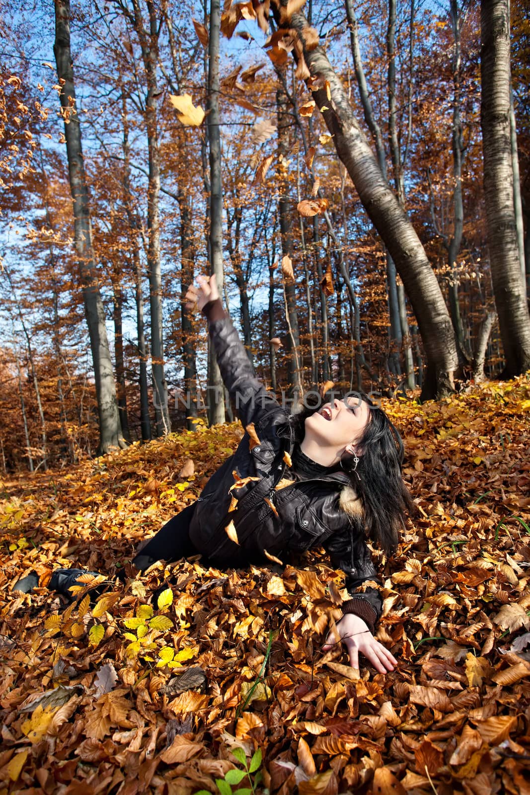 Young woman lying in fallen autumn leaves