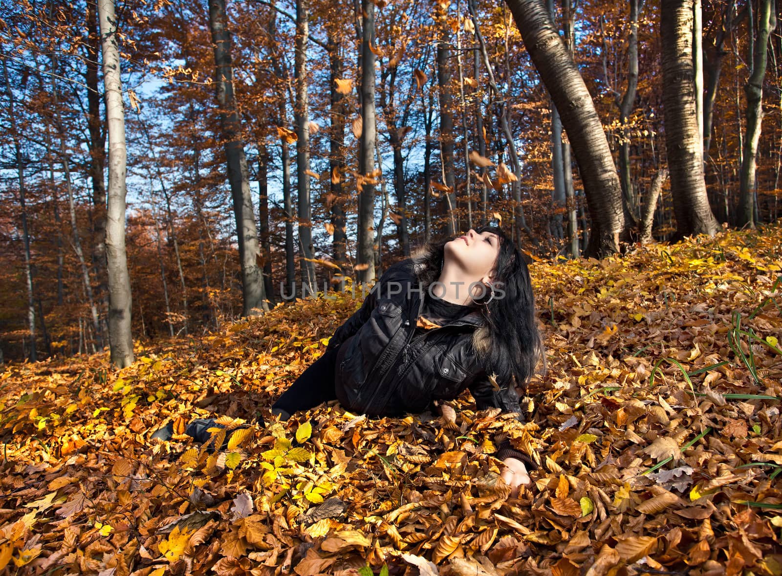Young woman lying in fallen autumn leaves
