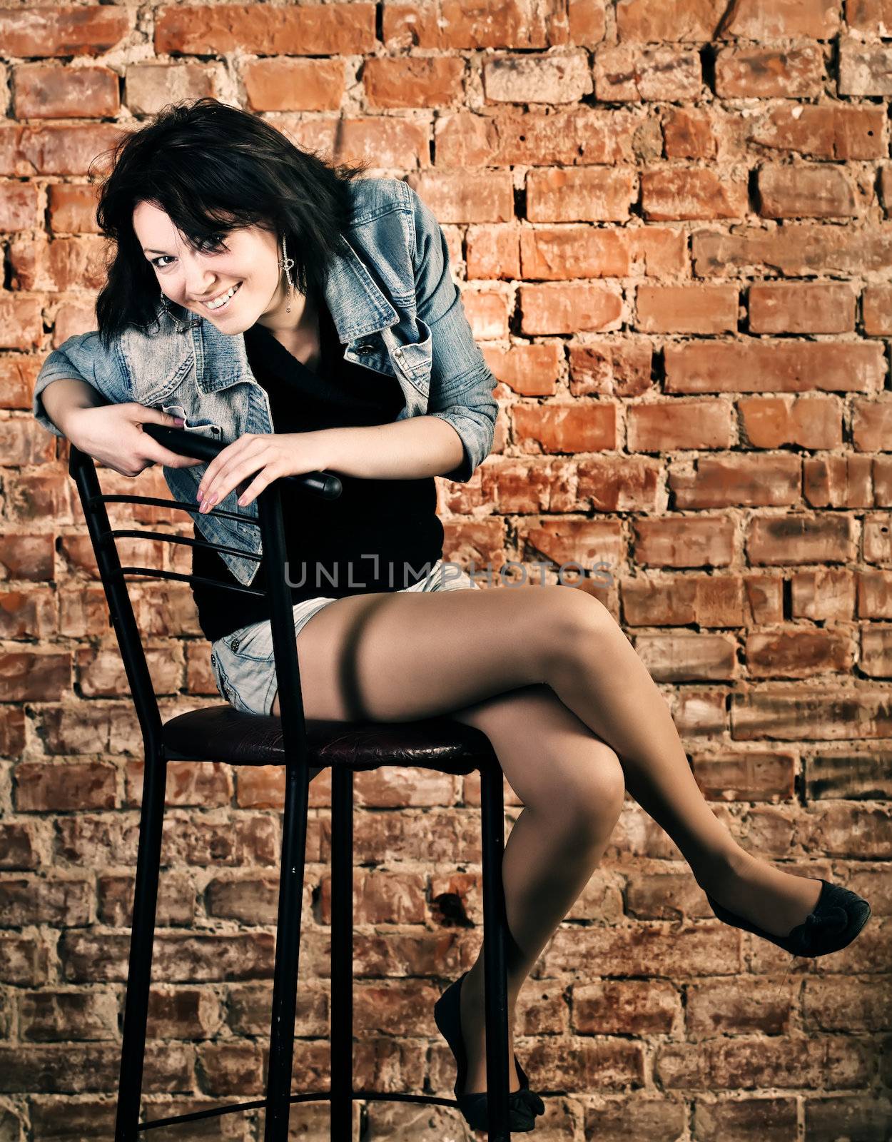Smiling young woman sitting against brick wall background