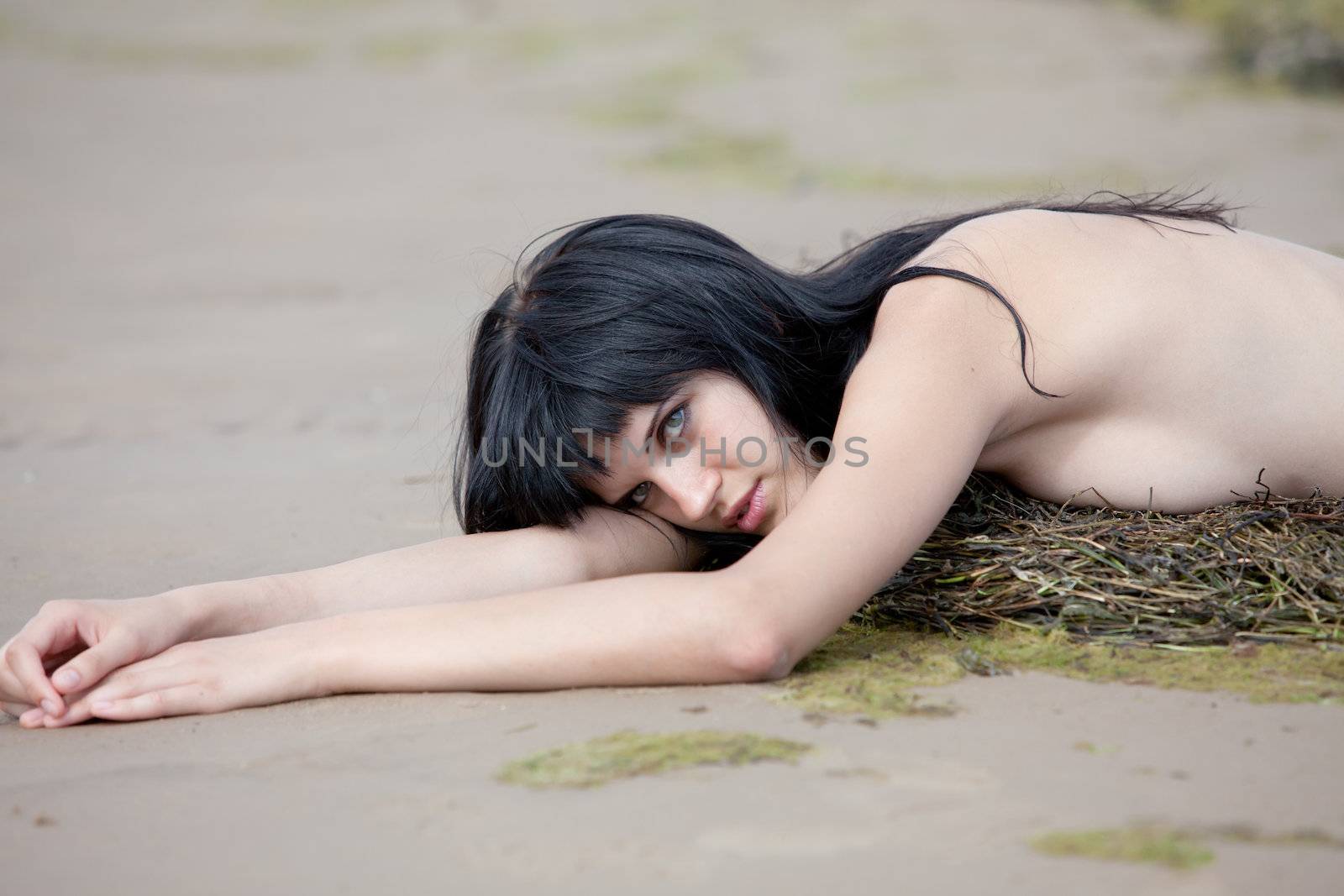 Young nude woman lying on the sand