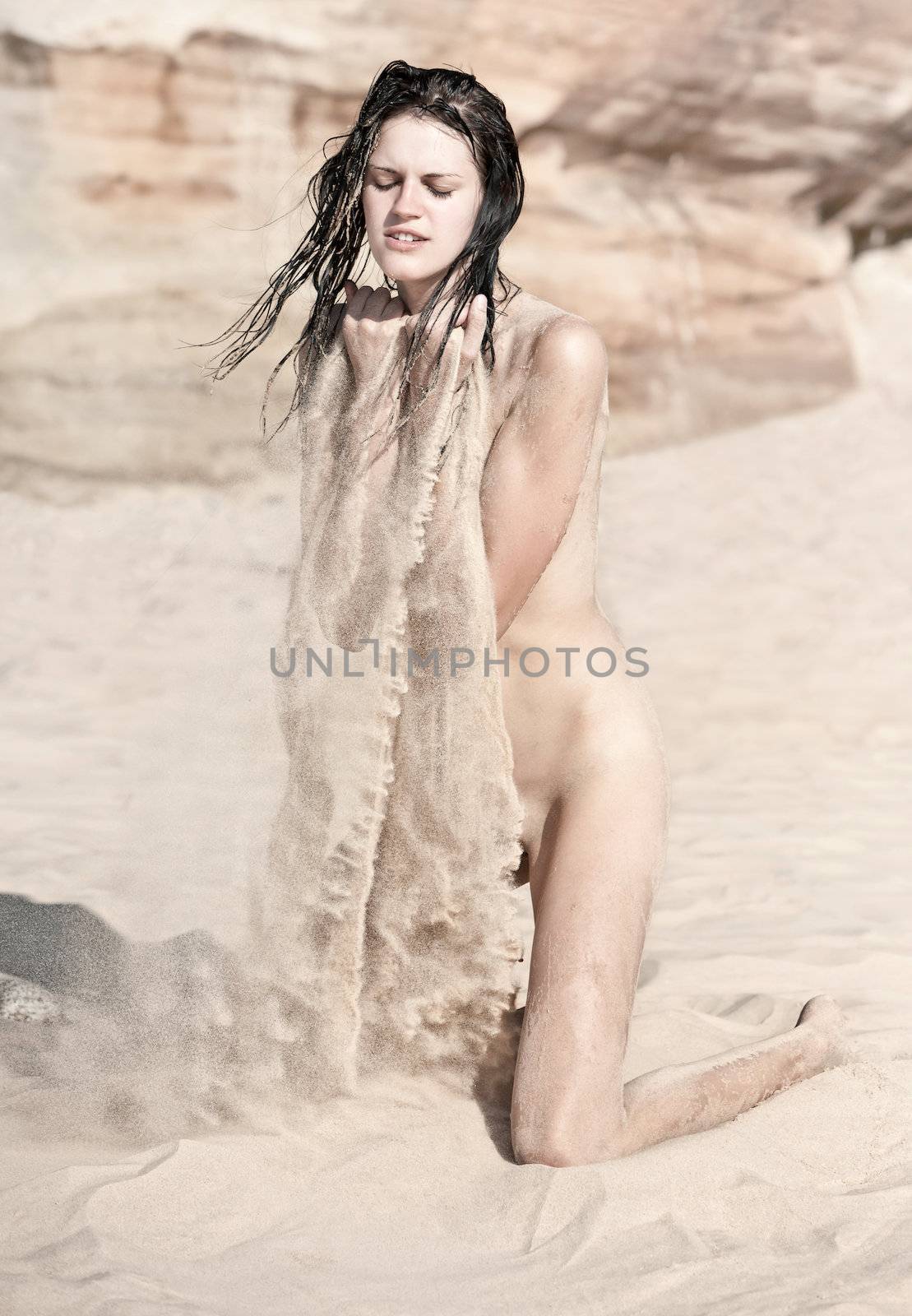 Sexy nude woman  playing with the sand
