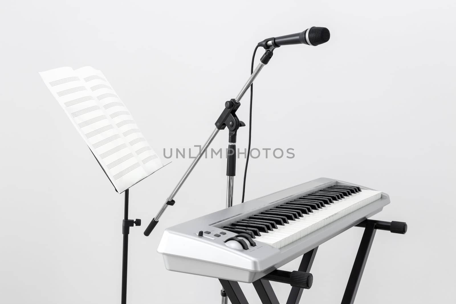 Electric piano, microphone and stand with sheet music.