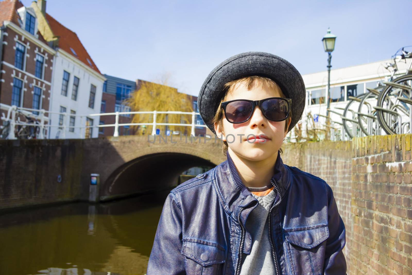 Handsome boy in sunglasses against canal background by Tetyana