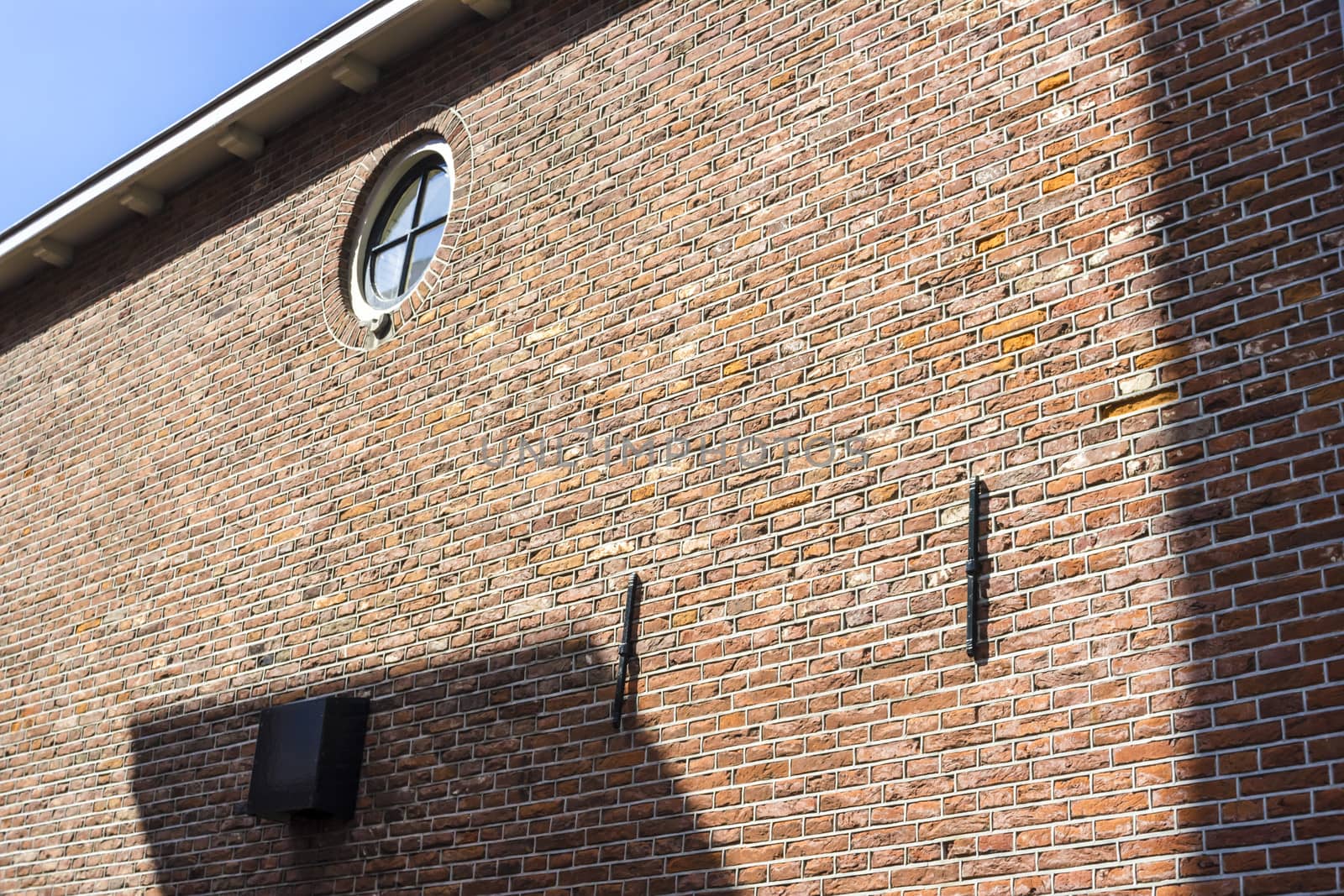 Round window on brick wall with clear blue sky, Alkmaar, the Netherlands